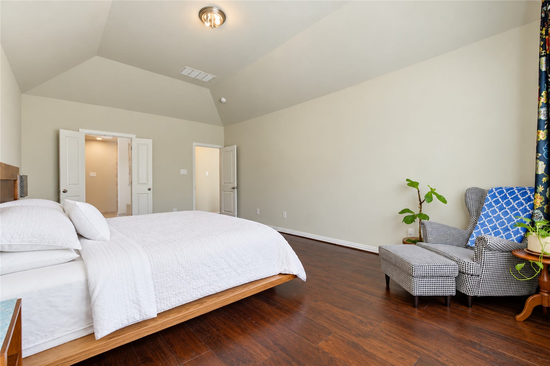 The first-floor primary suite offers peaceful backyard views, soaring vaulted ceilings, and abundant space to accommodate a king-sized bedroom set along with a comfortable sitting area.