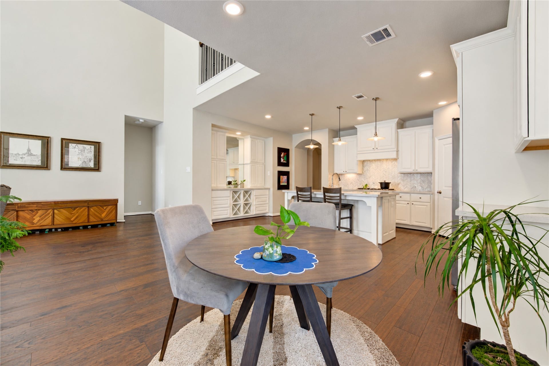 The dramatic double-height ceiling creates a grand, airy feel in the living room, complemented by a tall gas fireplace with a stylish tile surround that serves as a striking focal point.