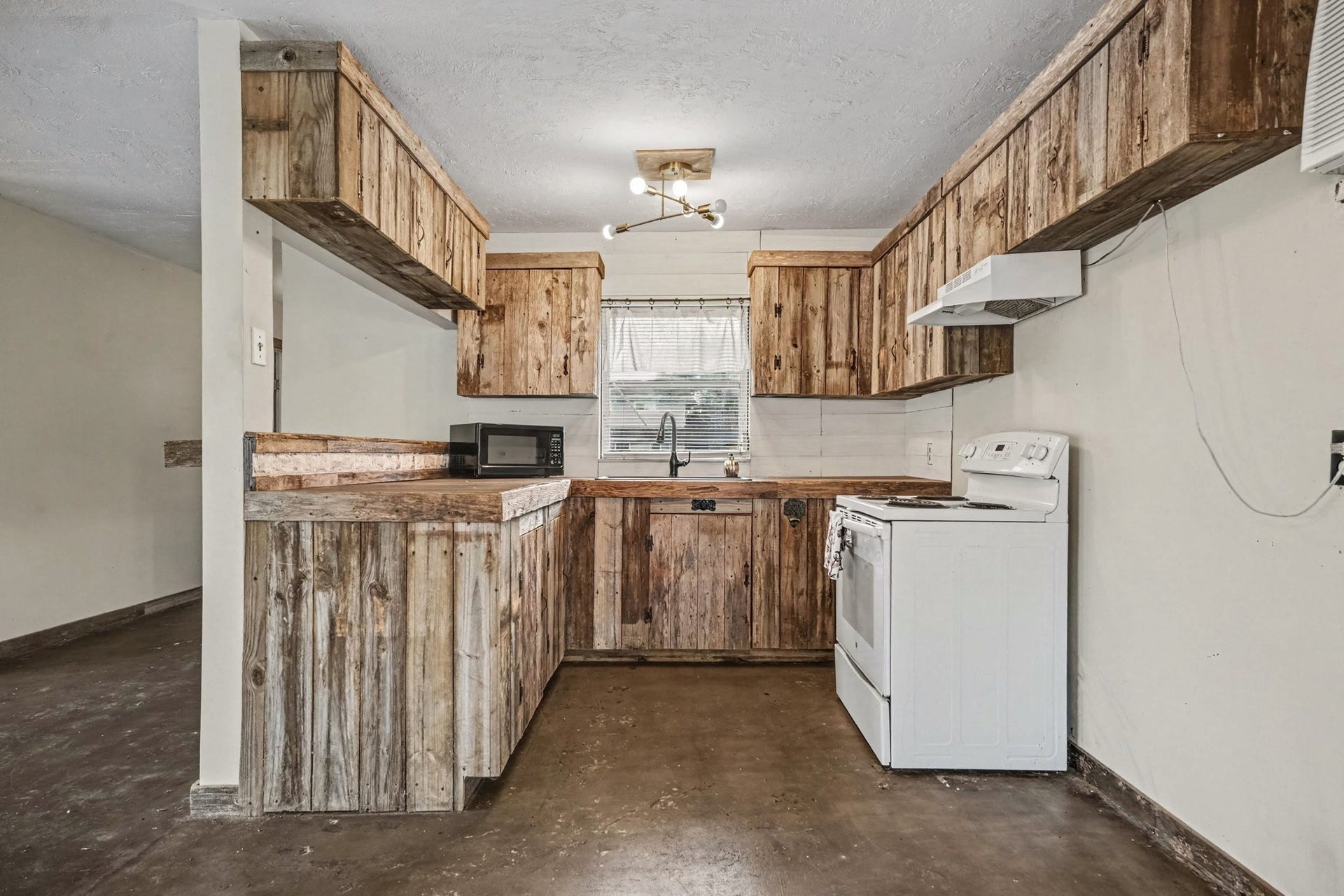3315 Saint Anne Street, Liverpool, TX 77577 Charming rustic kitchen with wooden cabinetry and countertops, featuring a cozy layout and ample natural light through a central window.