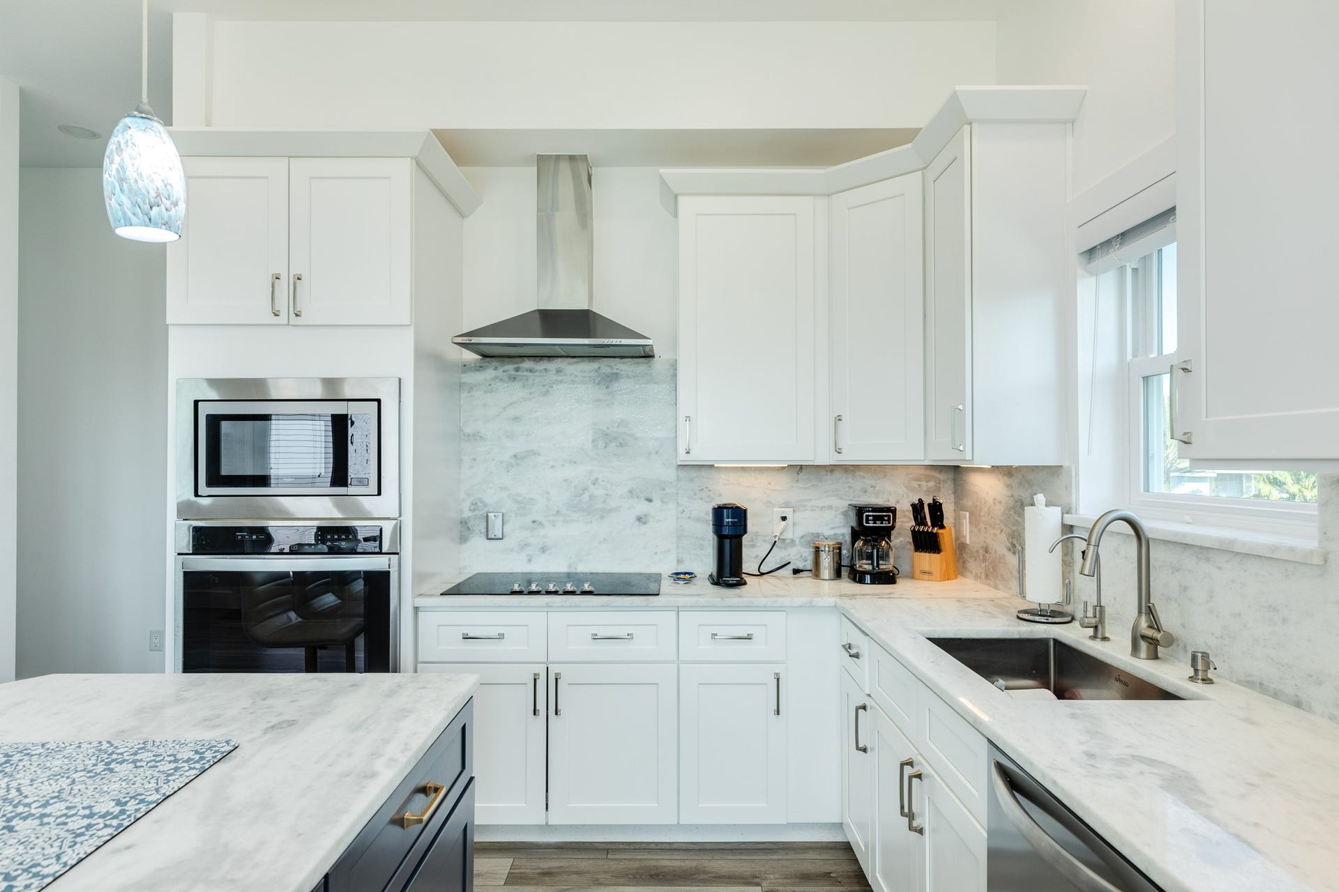 3903 Pirates Beach Blvd Court, Galveston, TX 77554 Kitchen detail view. Electric 5 burner cooktop with vent hood, separate electric oven with cabinet level microwave. Quartz countertops and backsplash accentuate the sleek finish of this kitchen.