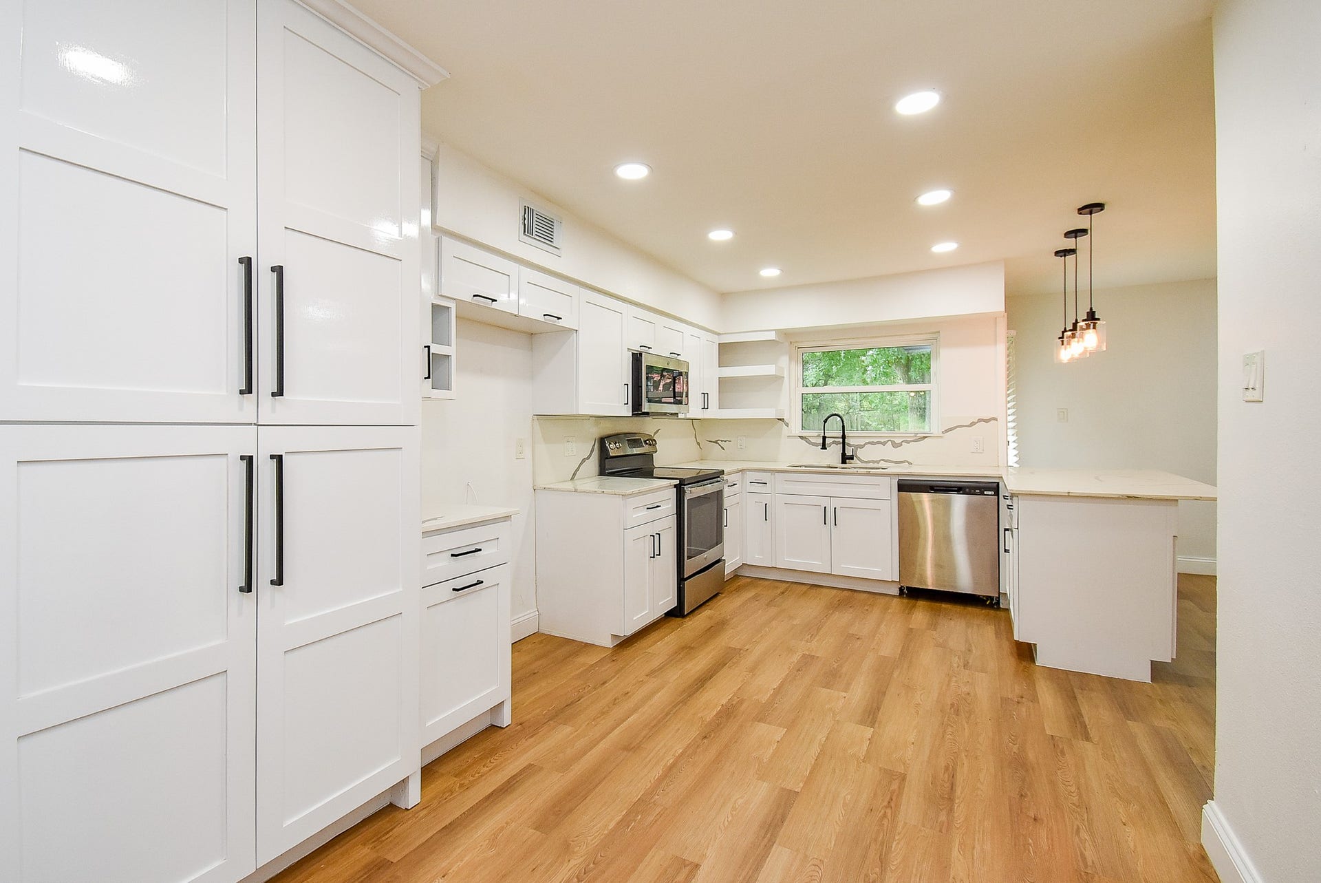 Bright kitchen with white cabinets, stainless steel appliances, and pendant lighting.