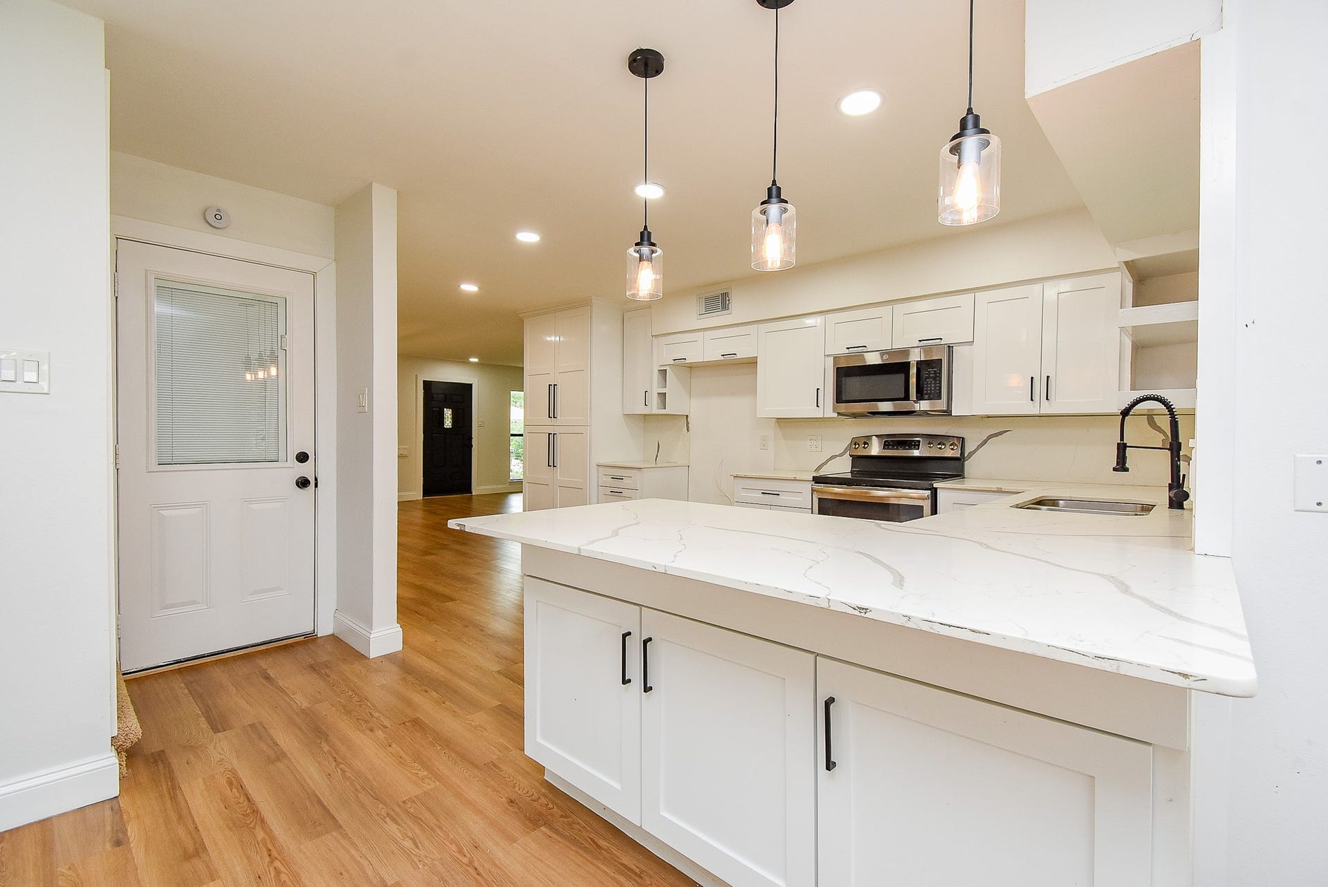 Modern kitchen with white cabinetry, stainless steel appliances, and a spacious marble countertop.