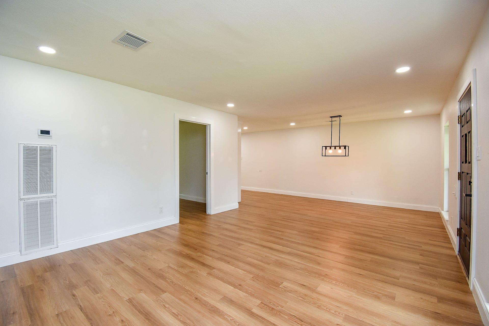 Spacious living area with wood floors, recessed lighting, and a modern chandelier.