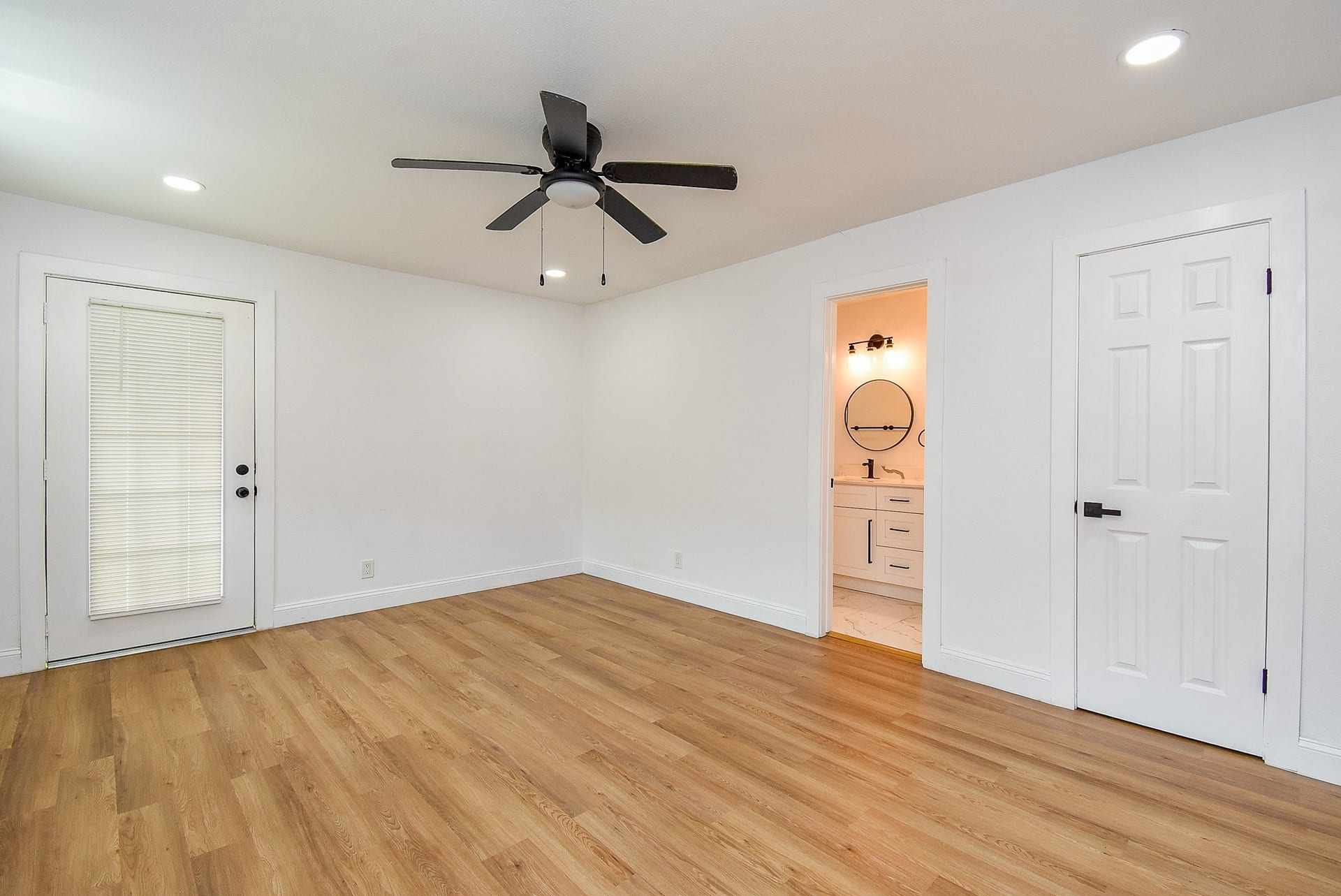 Bright room with hardwood floors, ceiling fan, natural light, and en-suite bathroom.