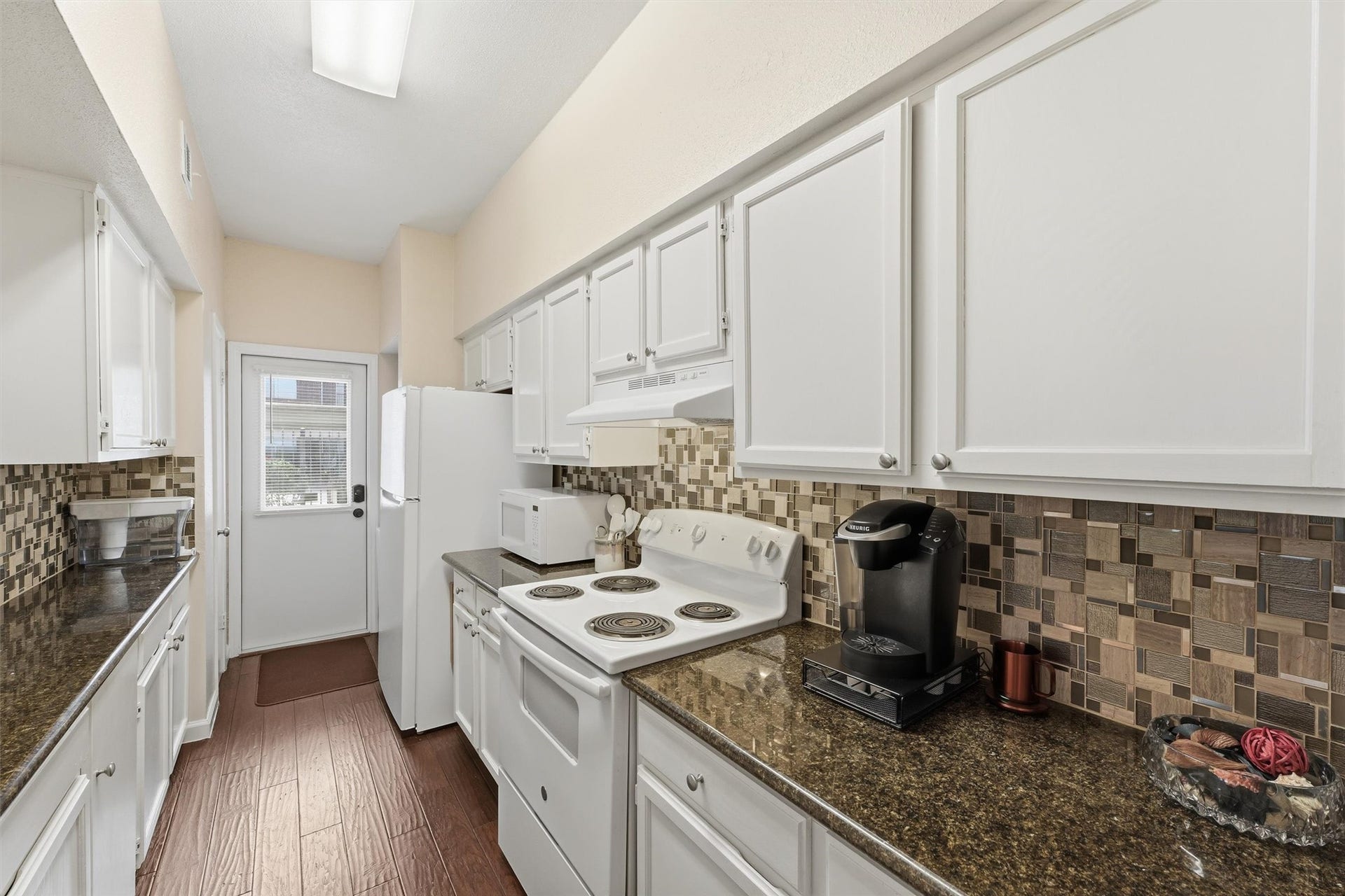 2425 Augusta Drive, #23, Houston, TX 77057 Kitchen facing back door w/ stackable washer and dryer next to refridgerator