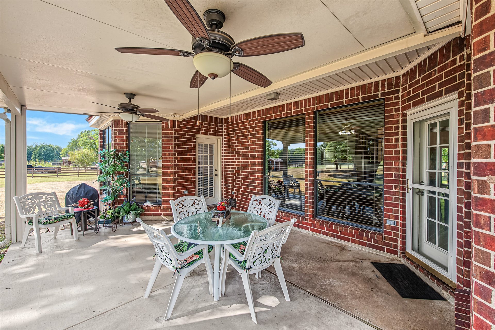 1345 Peach Ridge Road, Brookshire, TX 77423 Designed for seamless indoor-outdoor living, this expansive covered back patio features a durable concrete slab, dual outdoor ceiling fans, and a classic red brick exterior finish.
