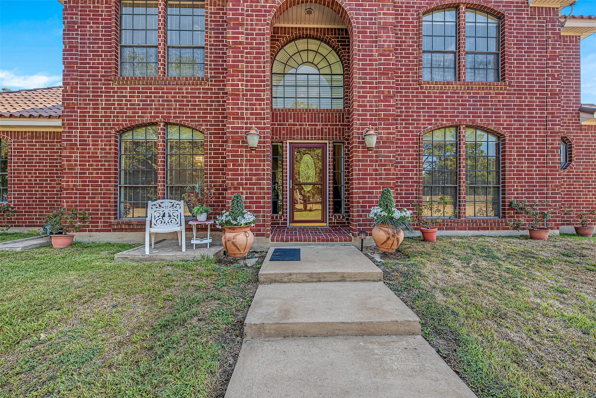 1345 Peach Ridge Road, Brookshire, TX 77423 Concrete steps lead gracefully up to the entrance across a vast, lush lawn shaded by mature trees, highlighting the stately symmetry and expansive presence of this country estate. Future clients will love the impressive, welcoming first impression this custom exterior makes from the moment they approach the home.