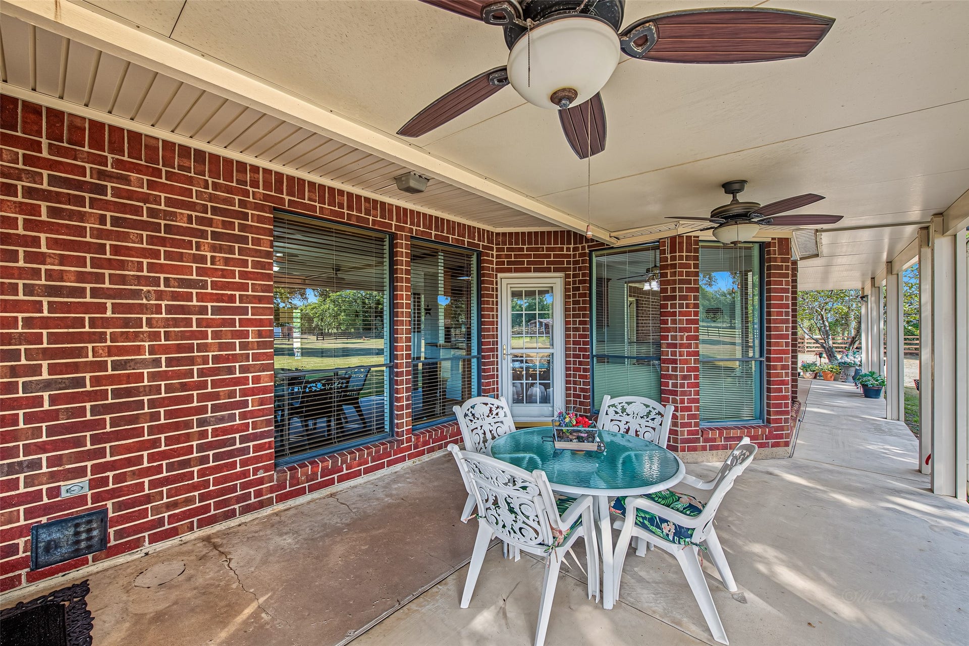 1345 Peach Ridge Road, Brookshire, TX 77423 Large picture windows and multi-pane glass doors connect the patio directly to the kitchen, dining nook, and primary suite, filling the home with natural light while providing easy access for outdoor dining and entertaining.