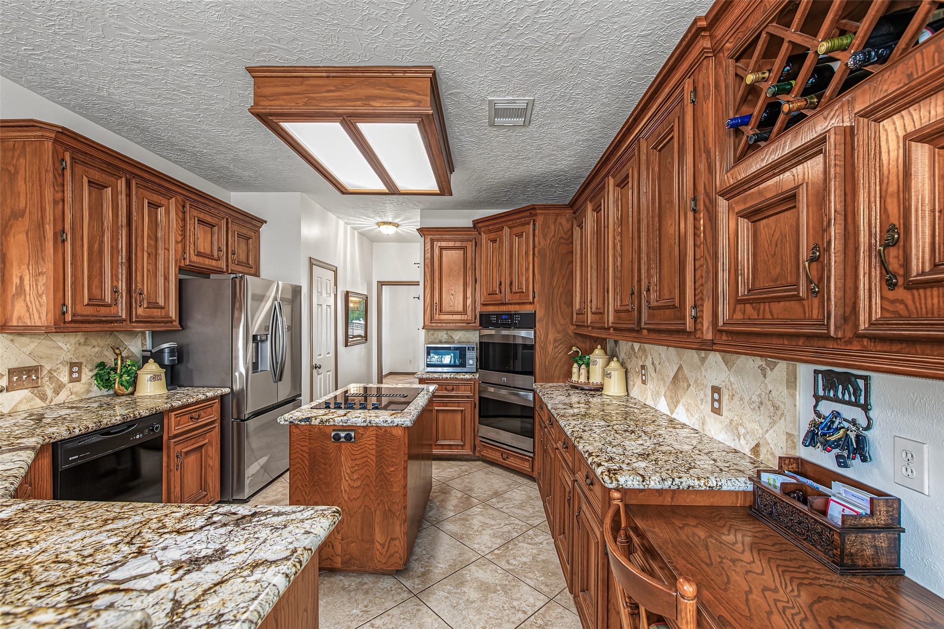 1345 Peach Ridge Road, Brookshire, TX 77423 Designed for both culinary precision and effortless entertaining, this chefs kitchen features expansive granite countertops, rich solid-wood cabinetry, and a full suite of stainless steel appliancesincluding built-in double ovens and a central cooktop island.
