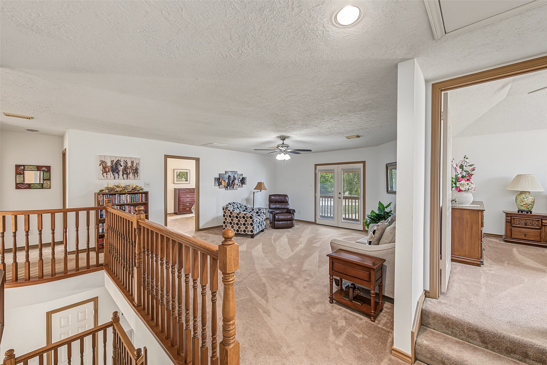 1345 Peach Ridge Road, Brookshire, TX 77423 At the top of the stairs, this expansive upper-level game room or secondary living lounge provides a versatile second gathering space surrounded by classic wooden balustrades overlooking the lower foyer.