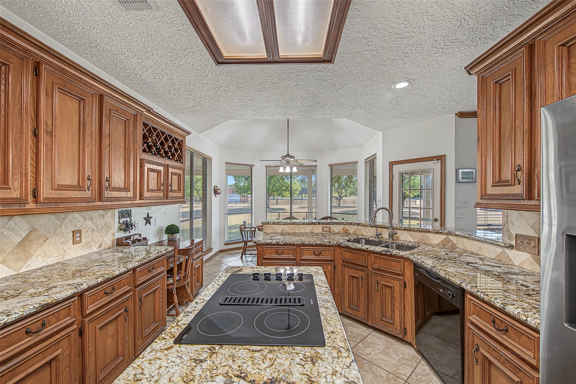 1345 Peach Ridge Road, Brookshire, TX 77423 Enclosed by stone-look tile flooring and framed wood lighting fixtures, this light-filled layout offers the ideal setting to host gatherings or enjoy quiet daily cooking.