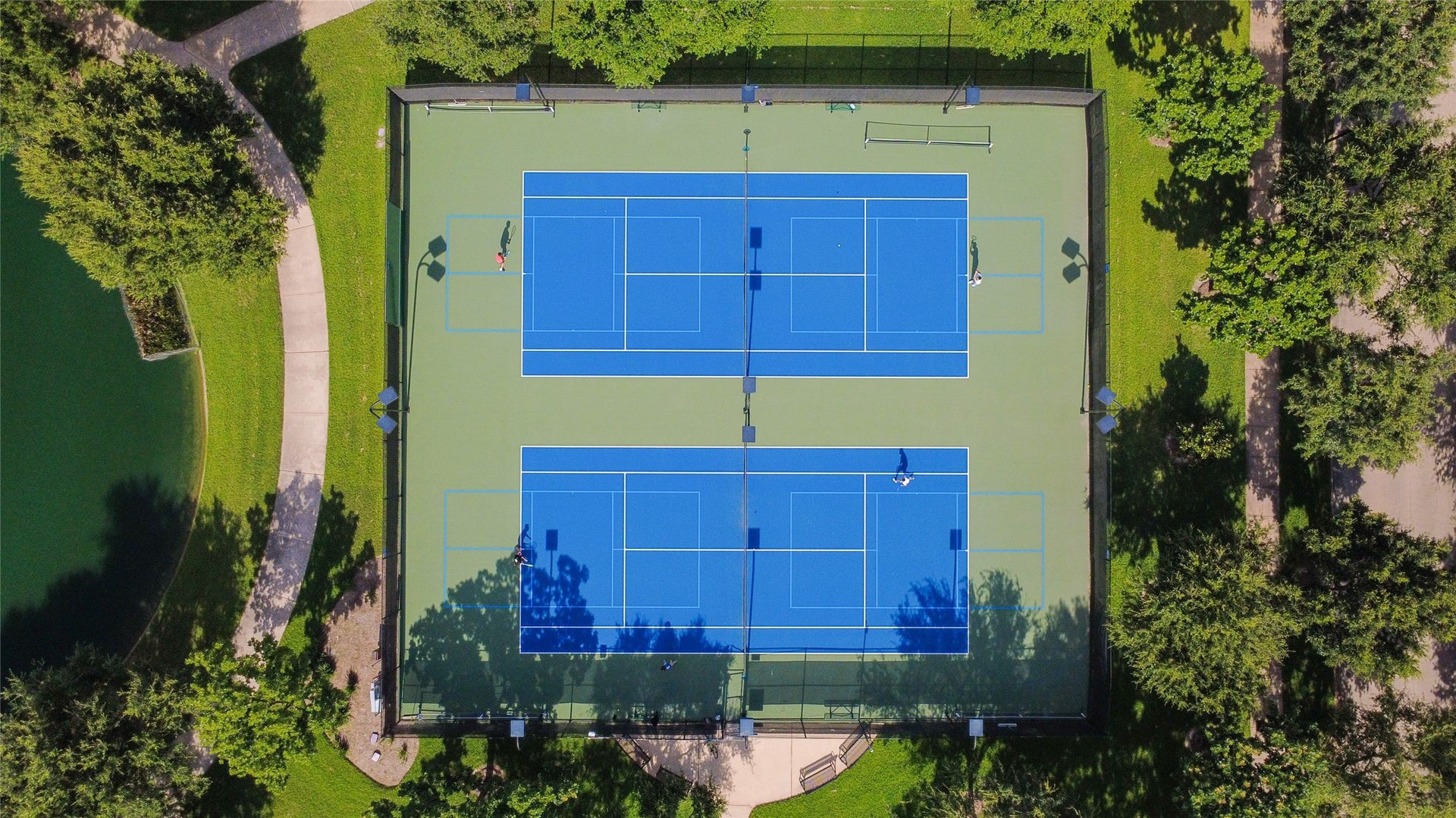 21123 Dover Park Lane, Katy, TX 77450 This aerial photo showcases two well-maintained tennis courts surrounded by lush greenery and walking paths, ideal for an active lifestyle in a serene setting.