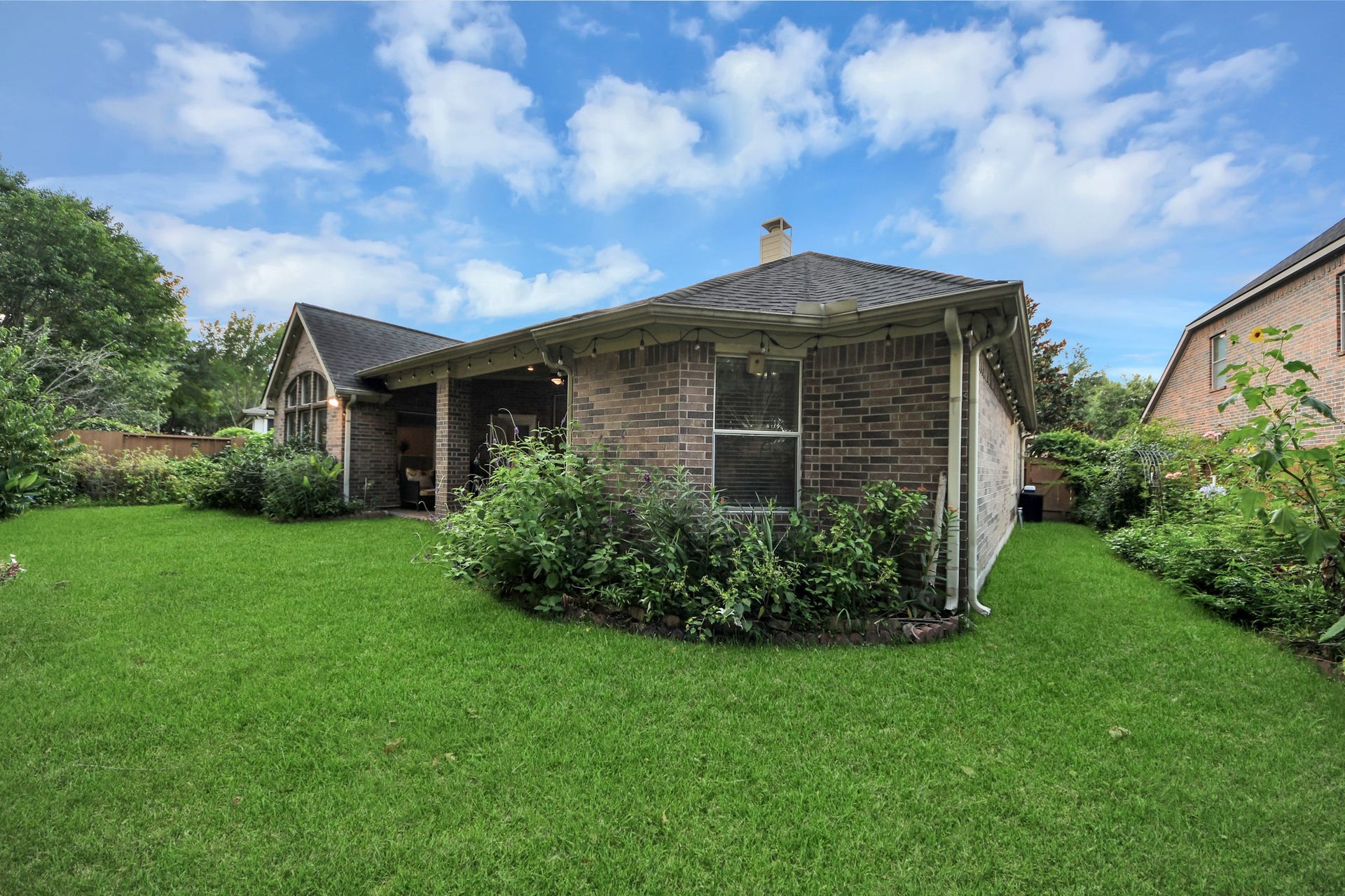 21123 Dover Park Lane, Katy, TX 77450 Charming brick home with a spacious, well-maintained backyard. Features a covered patio area, perfect for outdoor relaxation. Lush greenery surrounds the property, offering privacy and a serene atmosphere.