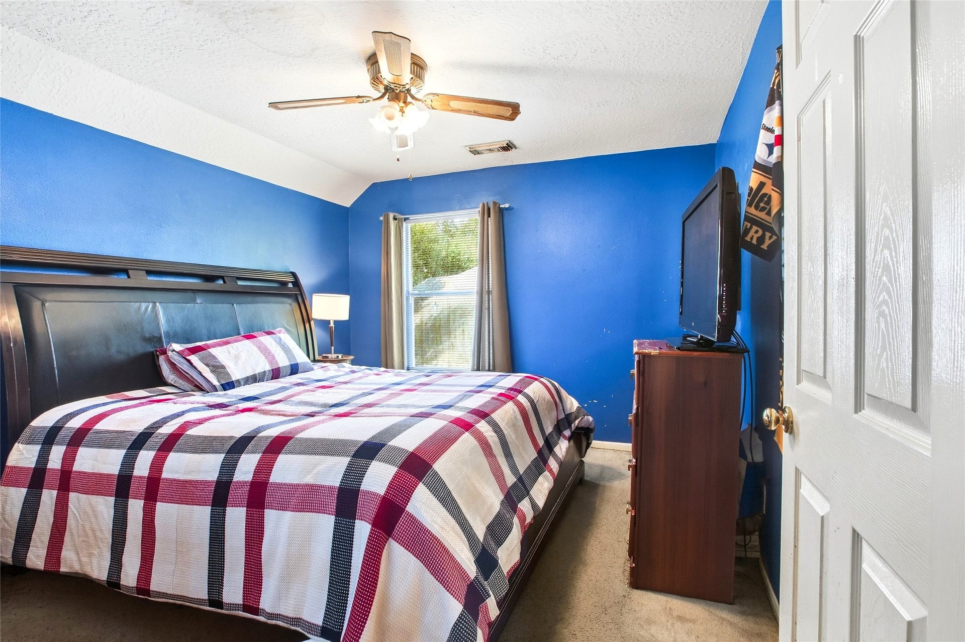 Secondary bedroom with carpet, ceiling fan, and window.