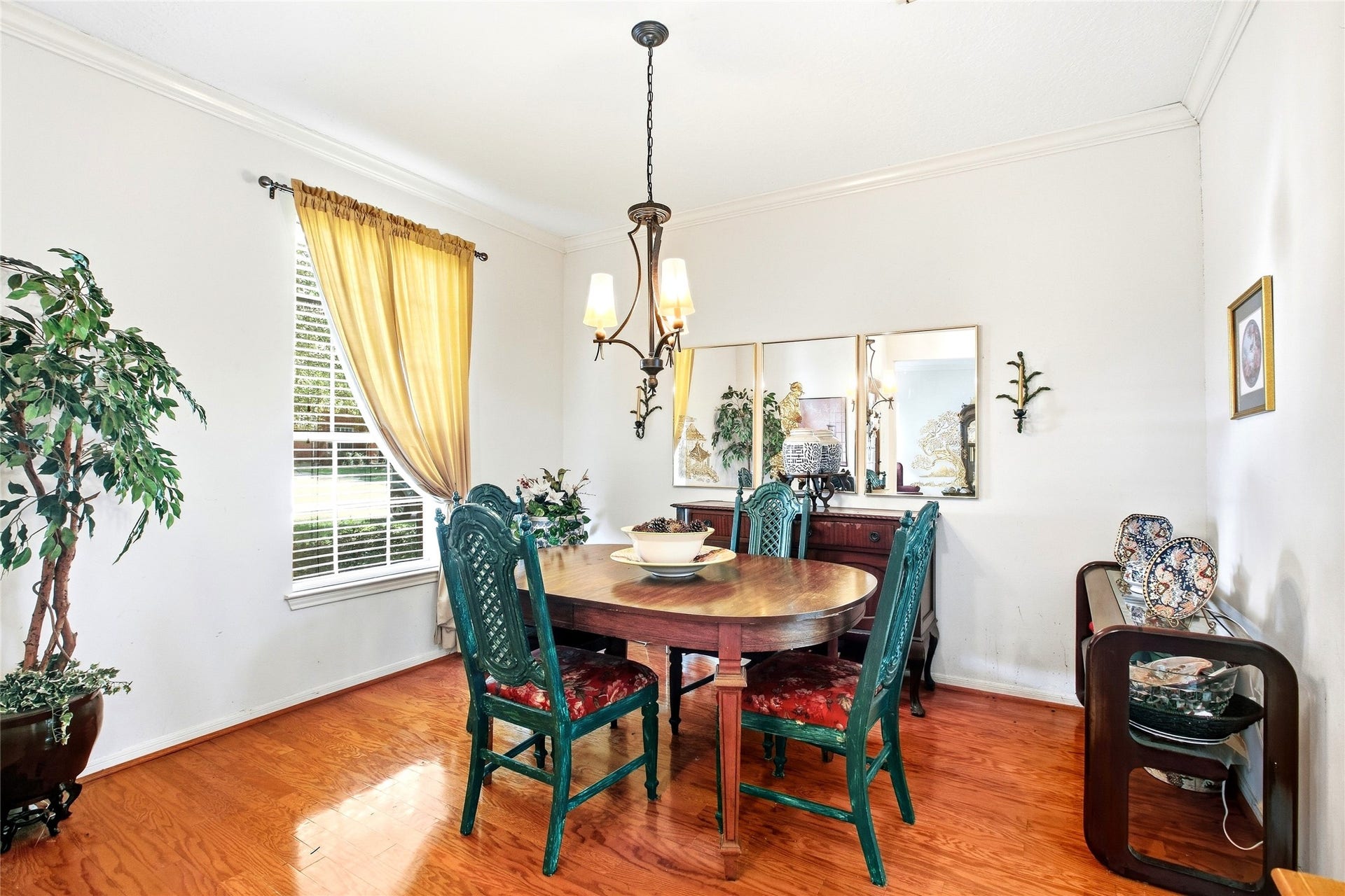 Formal dining room with a chandelier, crown molding, engineered wood floors, and window light.