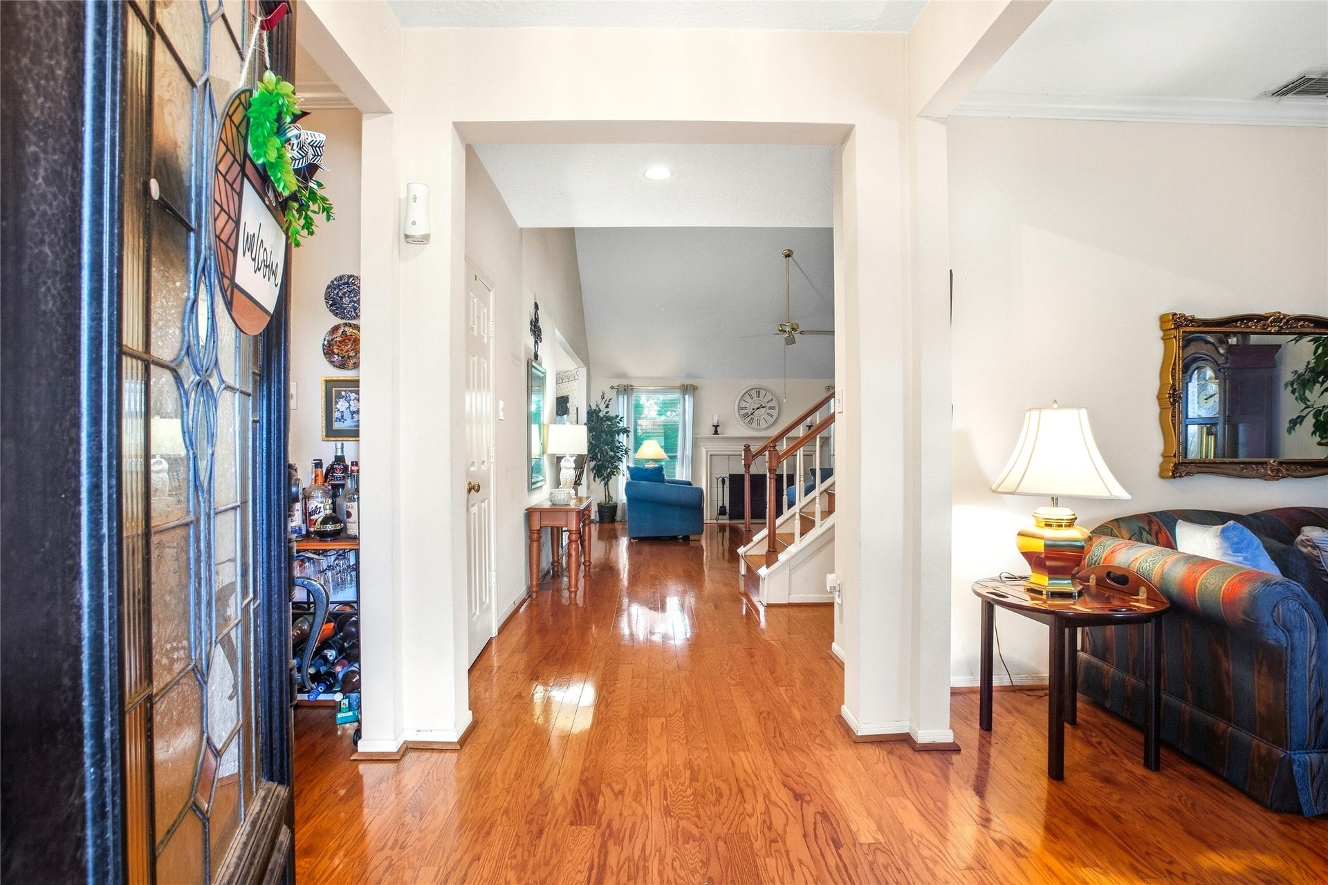 Entry foyer with engineered wood floors and clear sightlines to the family room and staircase, with the formal living room to the side.
