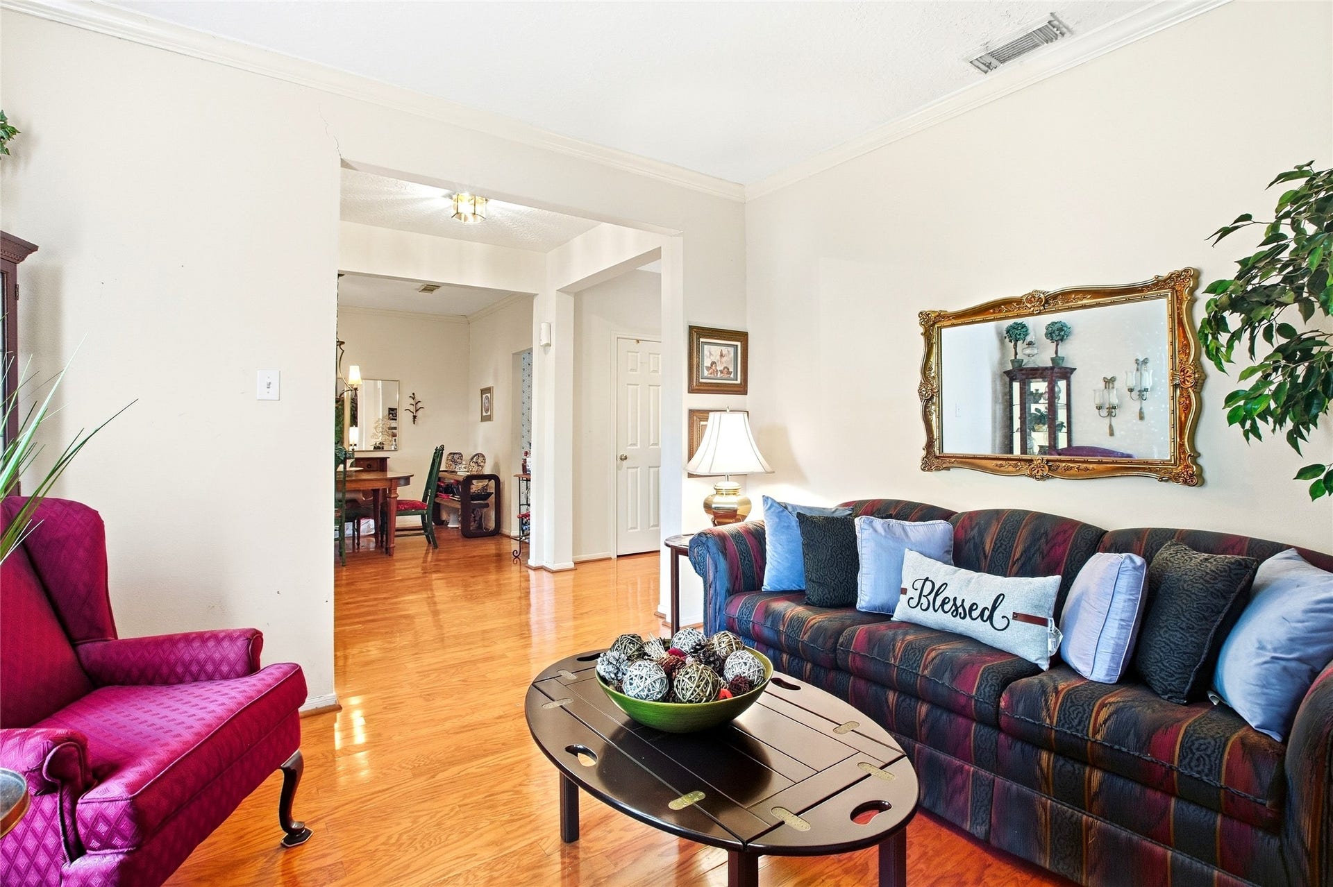 Formal living room with engineered wood floors and crown molding, open to the dining room and flexible for a study or sitting room.