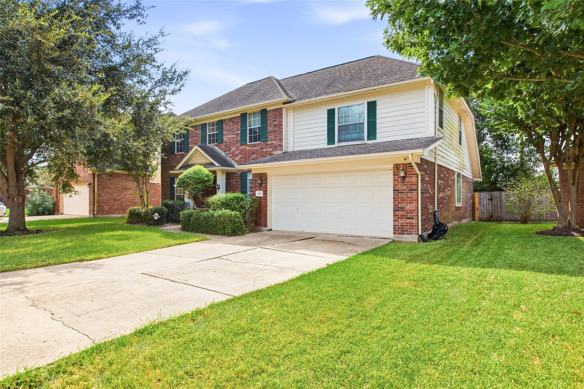 Angled front view showing the long driveway, attached two-car garage, and side-yard fencing.