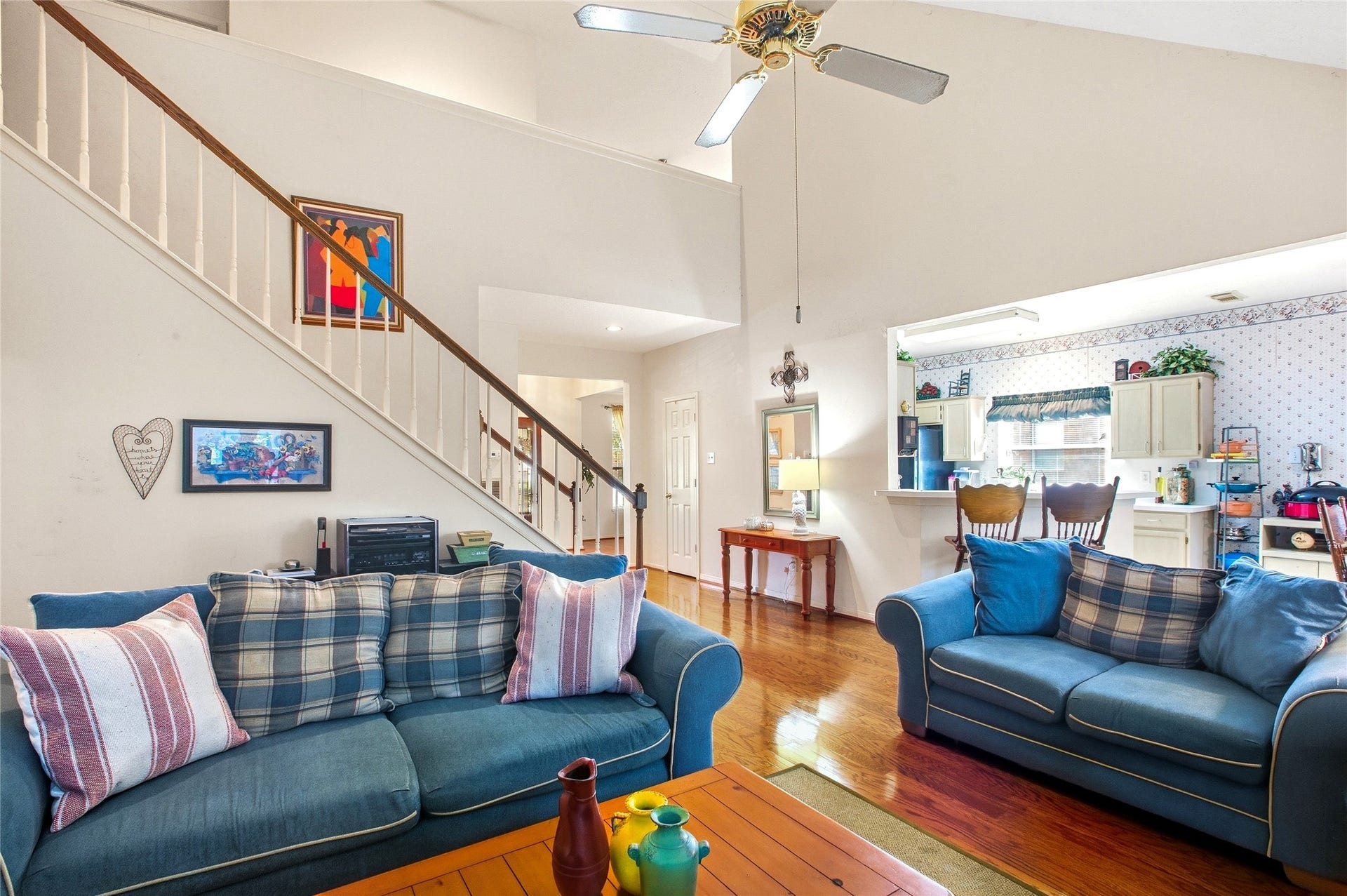 Open sightlines from the family room to the kitchen and staircase under a vaulted ceiling.