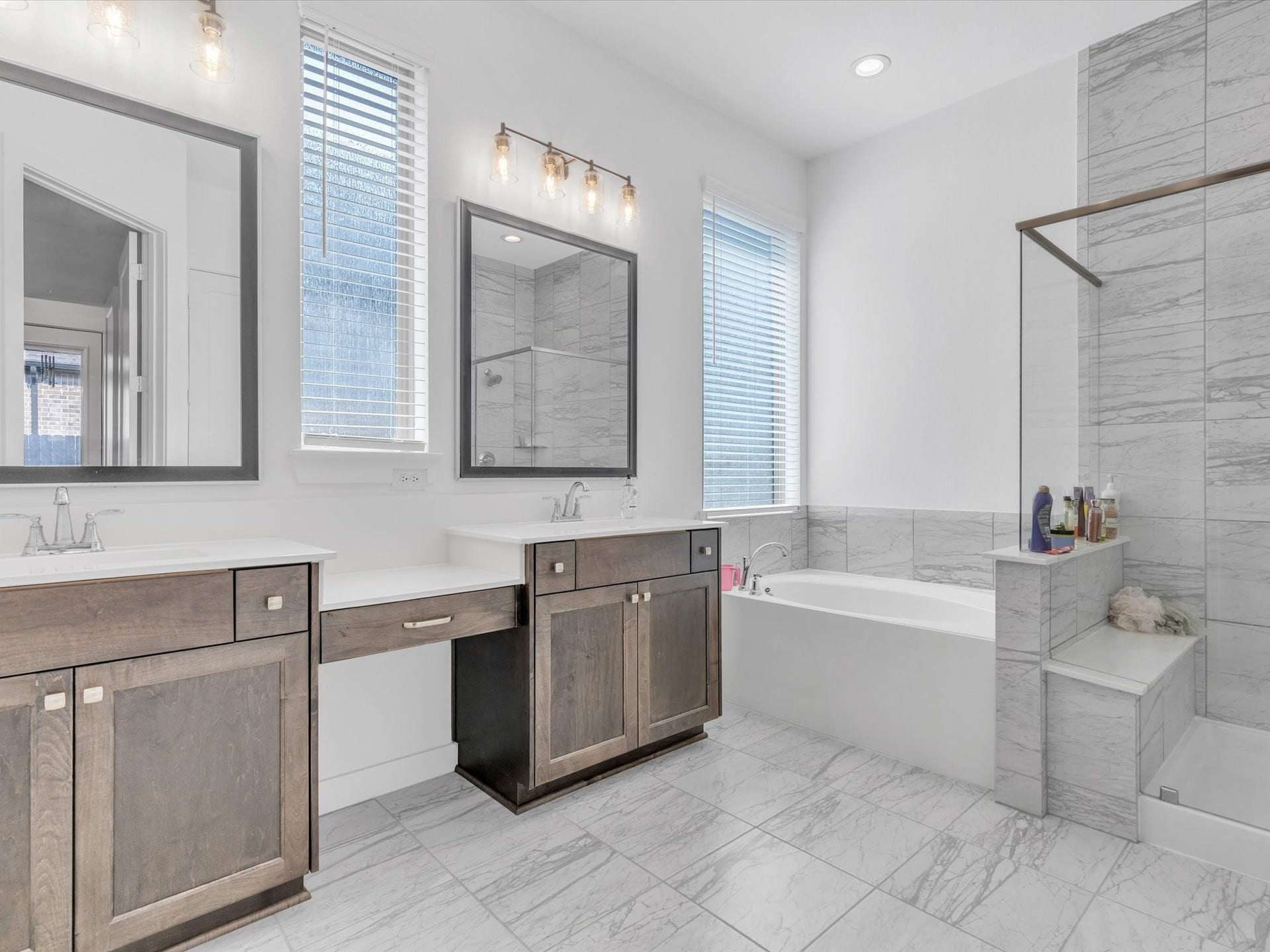 10718 Hidden Rock Drive, Missouri City, TX 77459 The impressive primary bath features dual vanities, a soaking tub and separate glass-enclosed shower surrounded by beautiful tile for a polished, relaxing retreat.