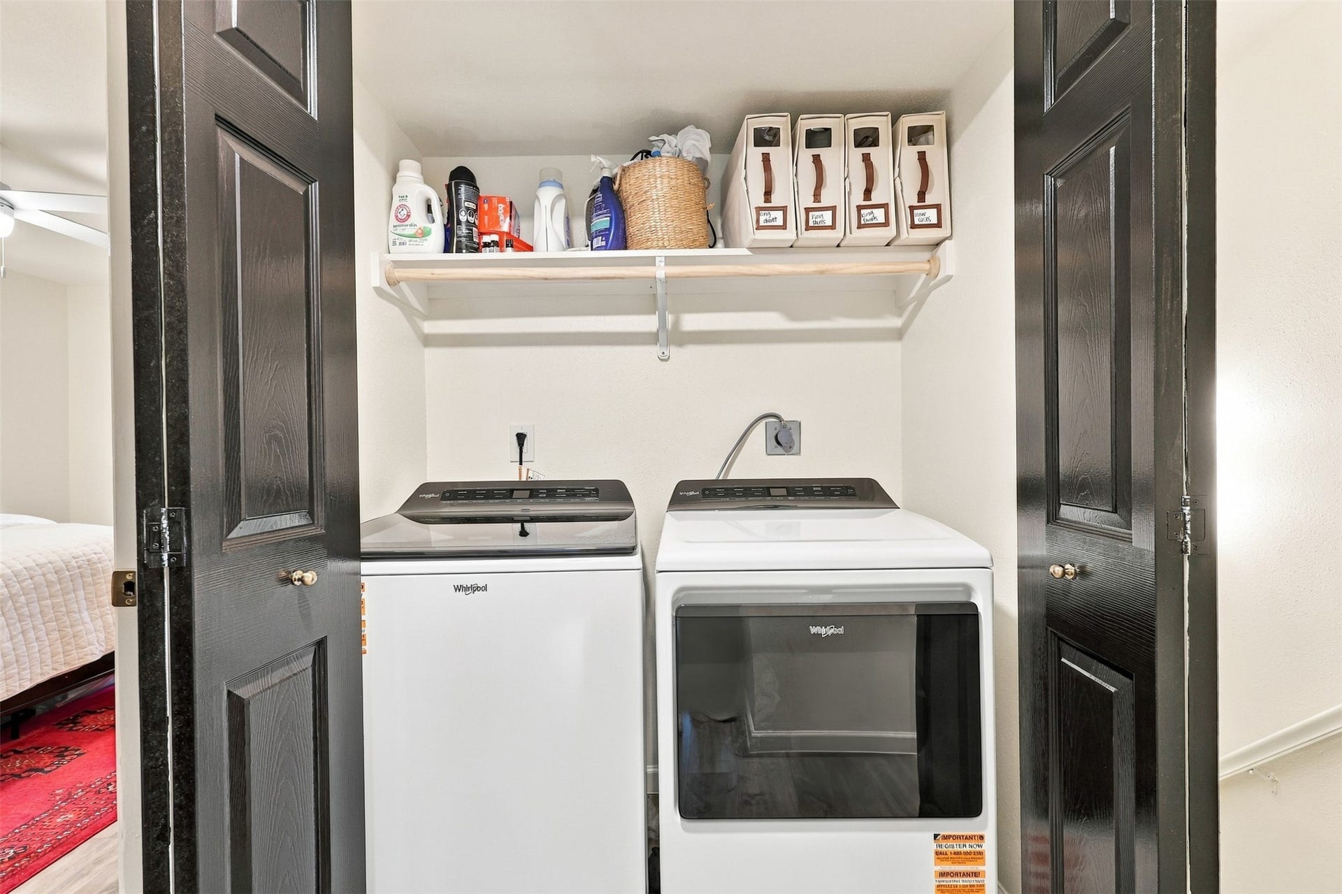 1201 Mcduffie Street, #212, Houston, TX 77019 Convenient laundry area with modern Whirlpool washer and dryer, neatly tucked behind sleek black doors, offering efficient and stylish functionality.