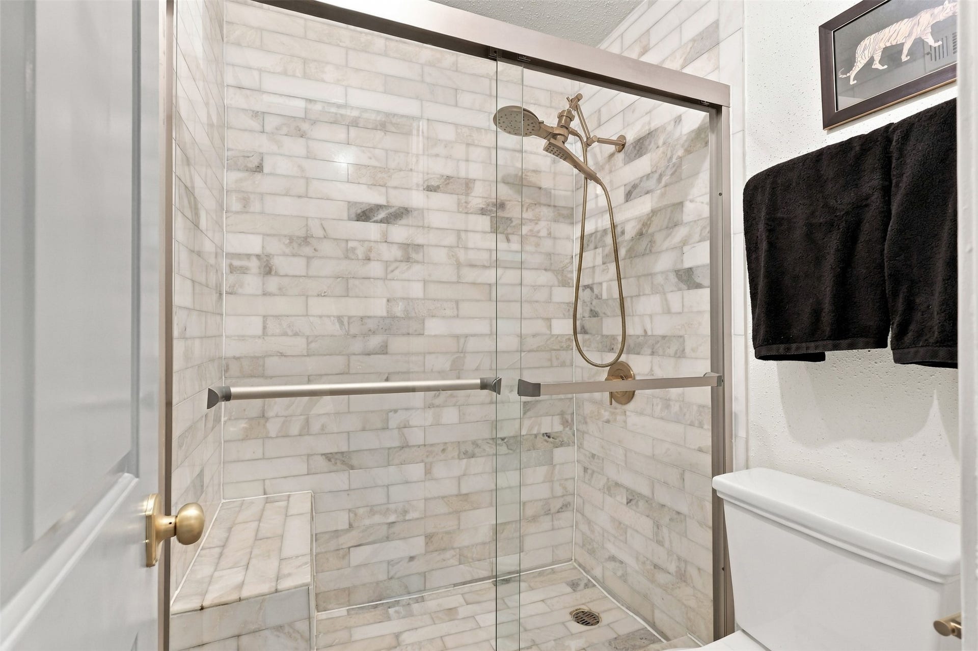1201 Mcduffie Street, #212, Houston, TX 77019 Elegant bathroom featuring a spacious walk-in shower with stylish marble tile and a sleek glass door, complemented by modern fixtures.