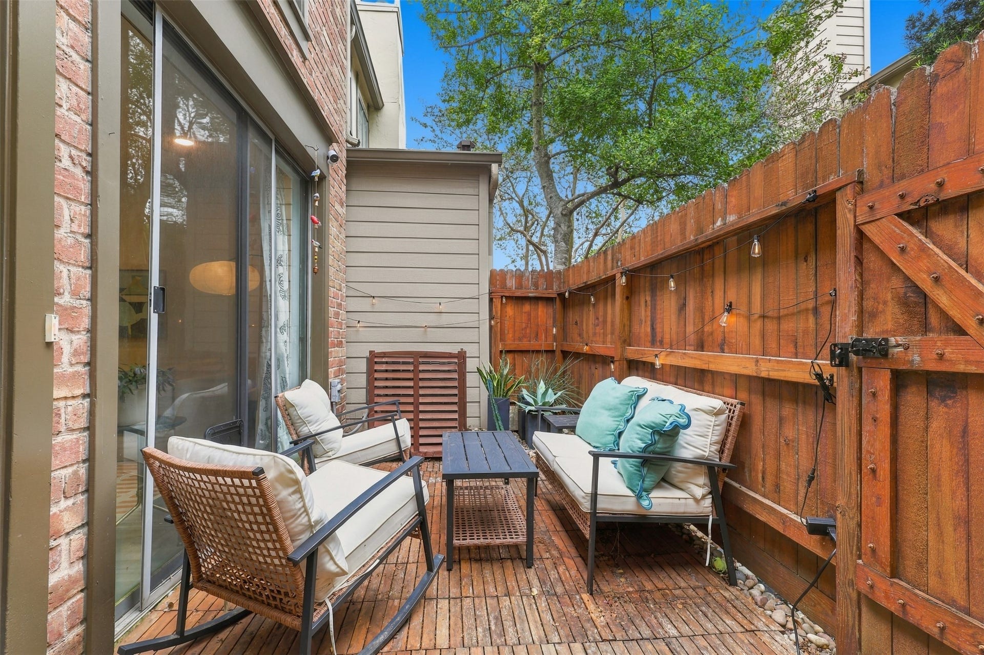 1201 Mcduffie Street, #212, Houston, TX 77019 Charming patio area with cozy seating, surrounded by a wooden privacy fence and lush greenery, perfect for relaxing outdoors.