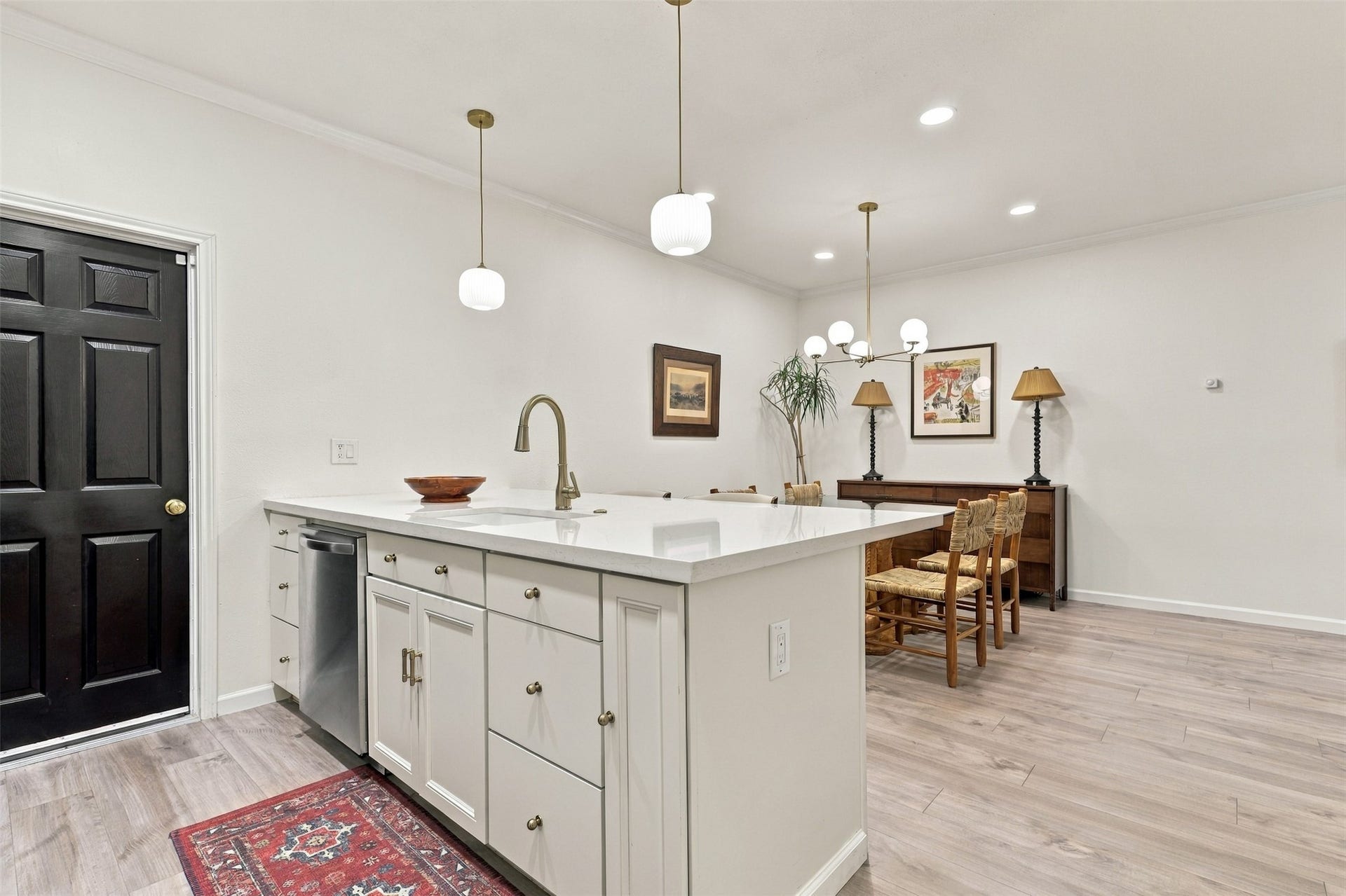 1201 Mcduffie Street, #212, Houston, TX 77019 Bright and modern kitchen-dining area featuring elegant pendant lighting, a spacious island with a sleek faucet, and stylish cabinetry, seamlessly connected to an inviting dining space with tasteful decor.