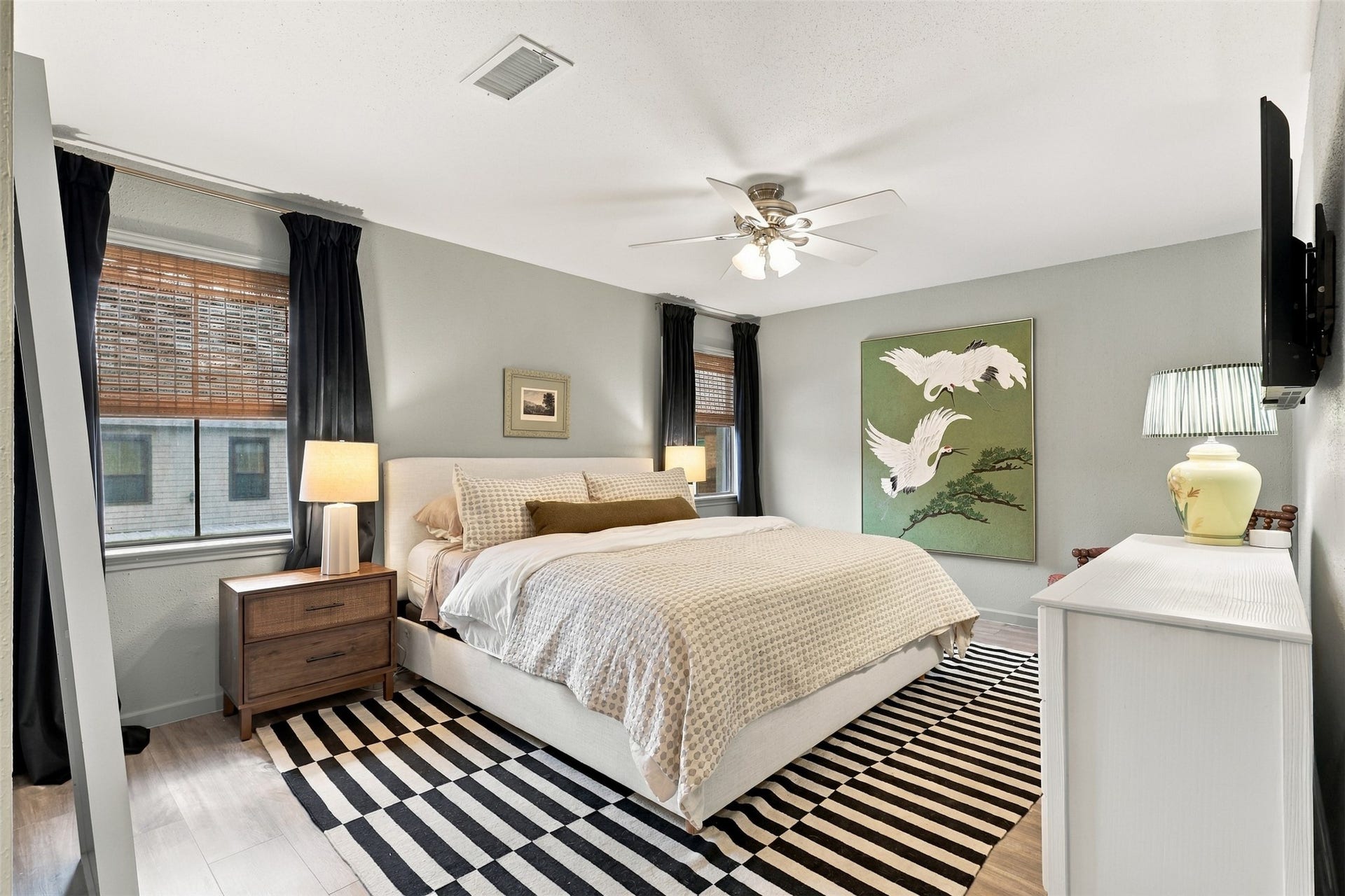 1201 Mcduffie Street, #212, Houston, TX 77019 A cozy bedroom featuring a plush bed, modern decor, and ample natural light, complemented by stylish art and elegant furnishings.
