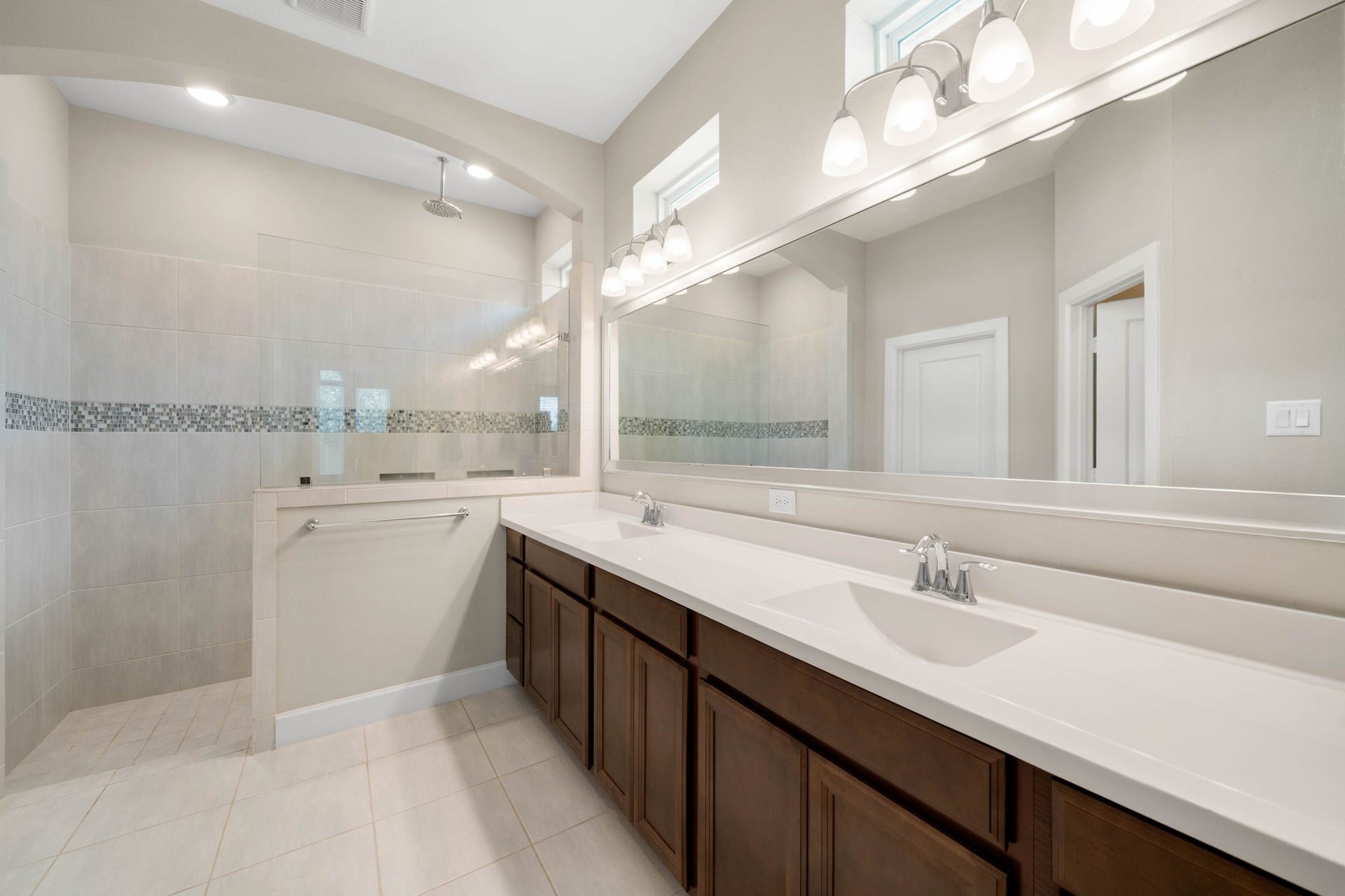 6922 Goldstrum Way, Katy, TX 77493 The spa-like primary bath features a double-sink vanity, a large mirror, and a spacious walk-in shower with a rain showerhead and tile surround.