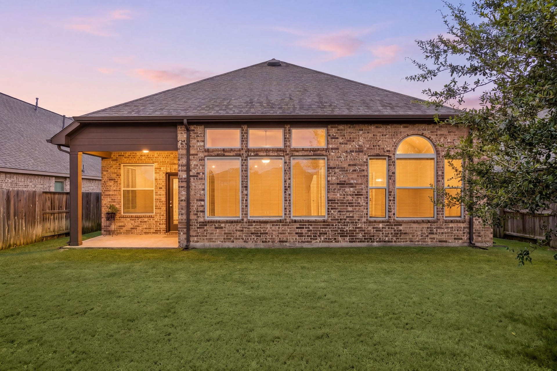 6922 Goldstrum Way, Katy, TX 77493 As evening falls, the backyard and covered patio glow with warm lighting, showcasing the home's peaceful outdoor setting.