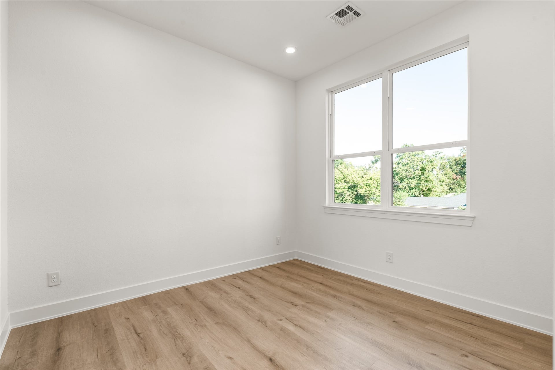 6714 Tierwester Street, Houston, TX 77021 A large window frames this secondary bedroom with views of the surrounding greenery, bringing an inviting connection to the outdoors.