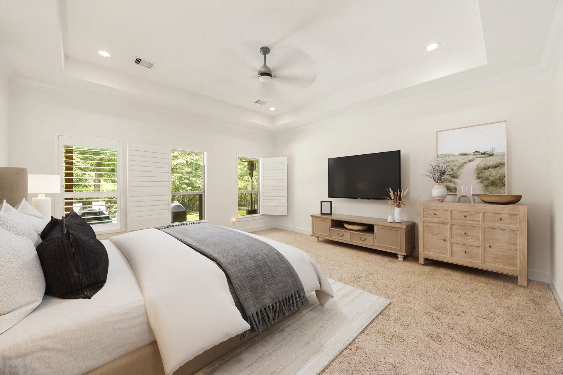 The spacious primary bedroom serves as a serene retreat, highlighted by an elegant deep tray ceiling and recessed lighting. Three large windows outfitted with plantation shutters fill the room with beautiful natural light while offering peaceful views of the surrounding greenery. *Virtually Staged.