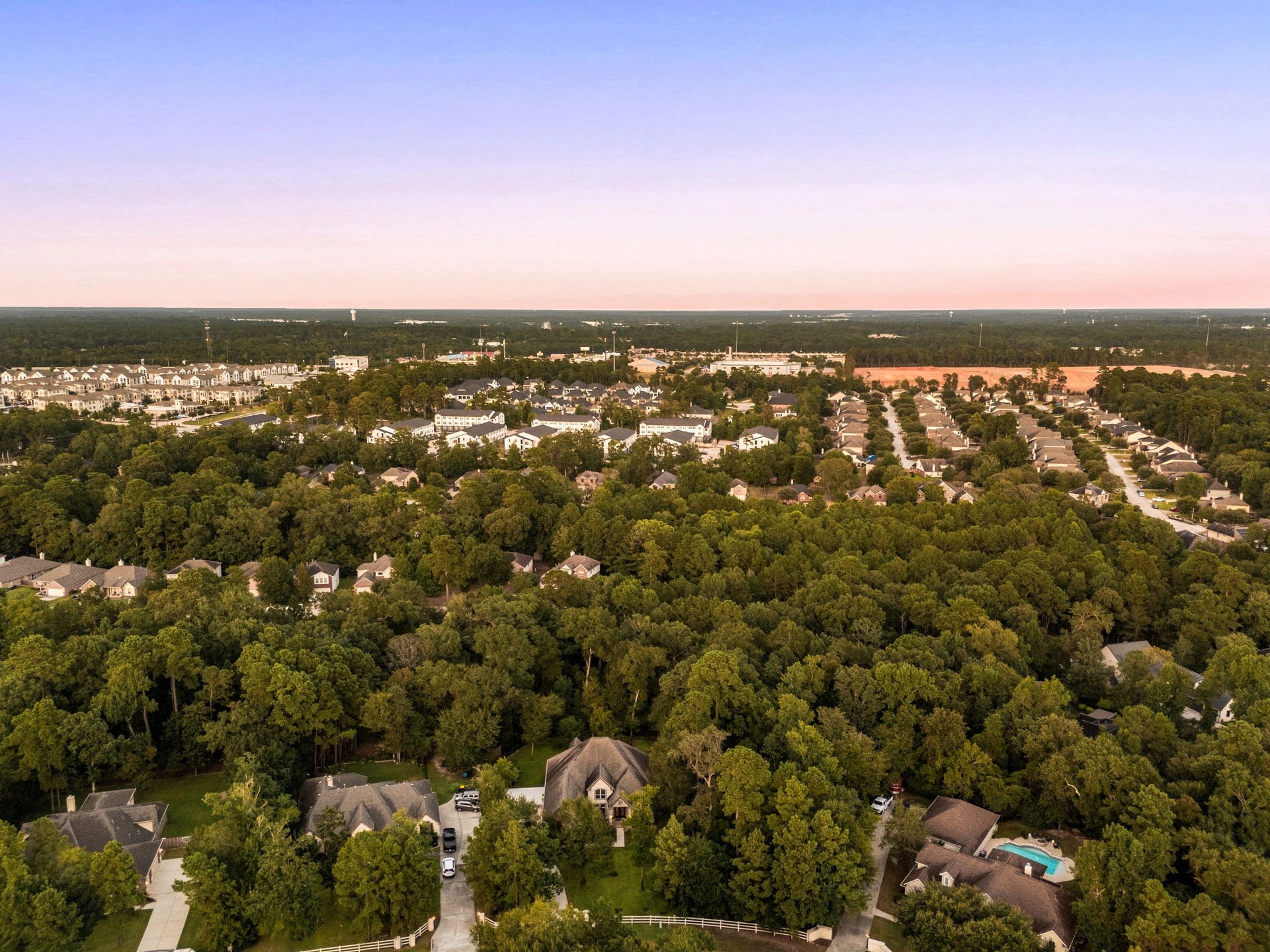 An aerial vantage point over Dominion Ridge captures the stunning, tree-lined landscape of this highly sought-after Conroe, Texas neighborhood. This expansive view showcases a seamless blend of private residential estates nestled in dense greenery and neighboring communities with Interstate-45 just a mile away.