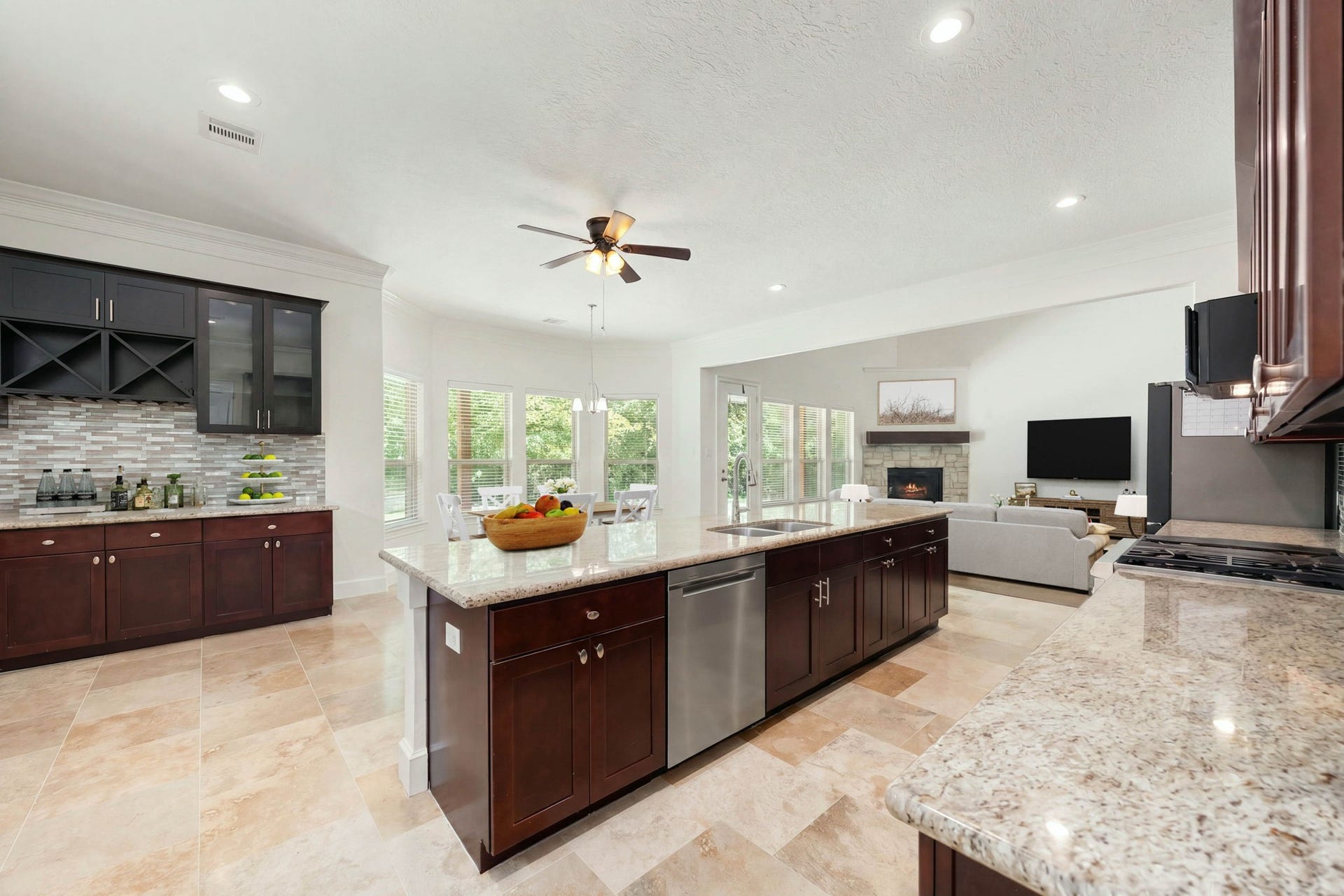 This expansive, open-concept design seamlessly connects the kitchen, dining area, and living room, making it perfect for entertaining. The bright space features a massive central island with a built-in stainless steel dishwasher, a built-in wine bar, and a wall of windows that overlooks the peaceful backyard.