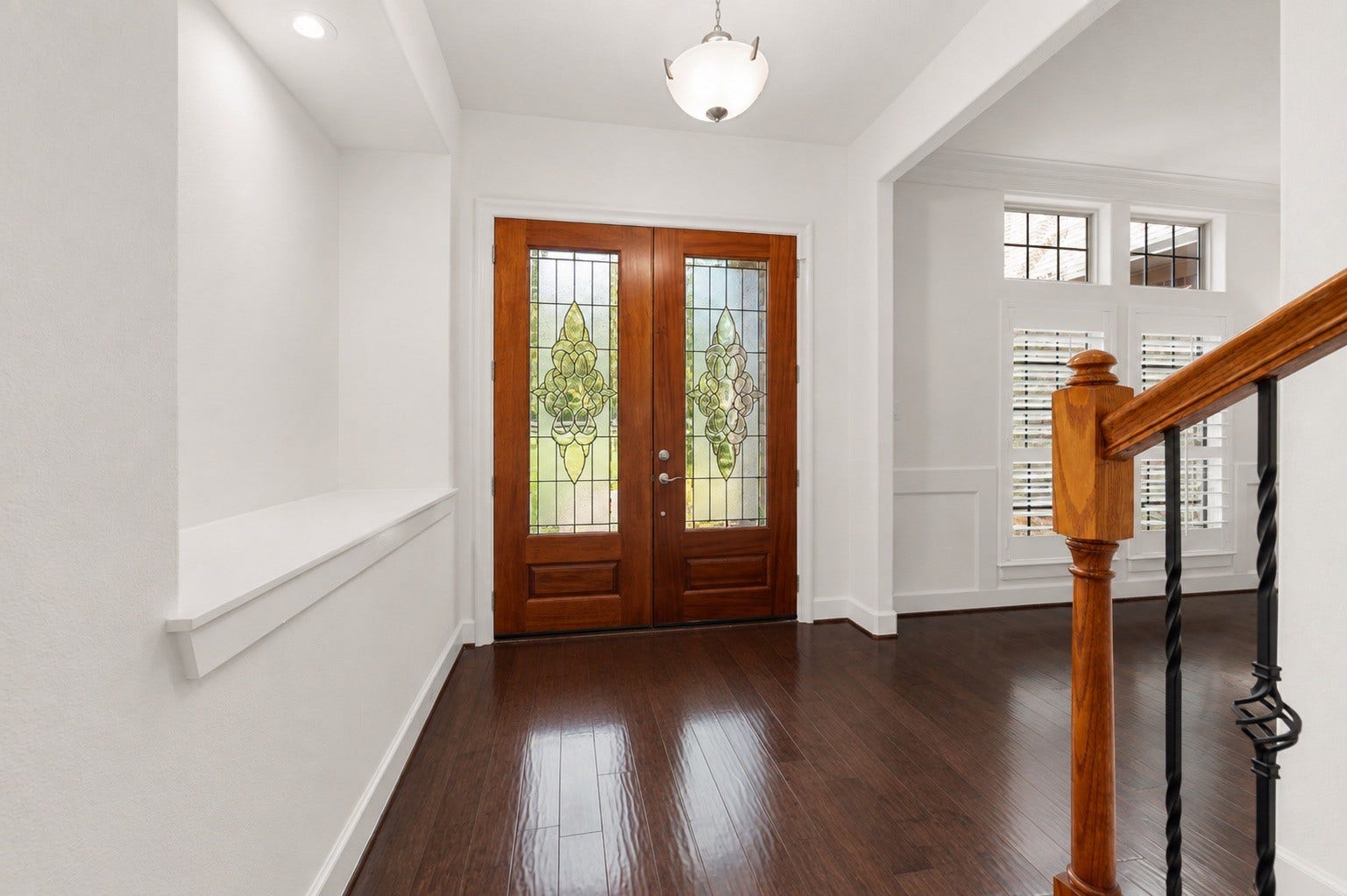 This bright and expansive entryway makes an unforgettable first impression! The double wood doors features detailed leaded glass panels. The sophisticated foyer also highlights premium craftsmanship, showcasing an elegant built-in art niche and custom trim work that flows beautifully into the adjoining rooms.