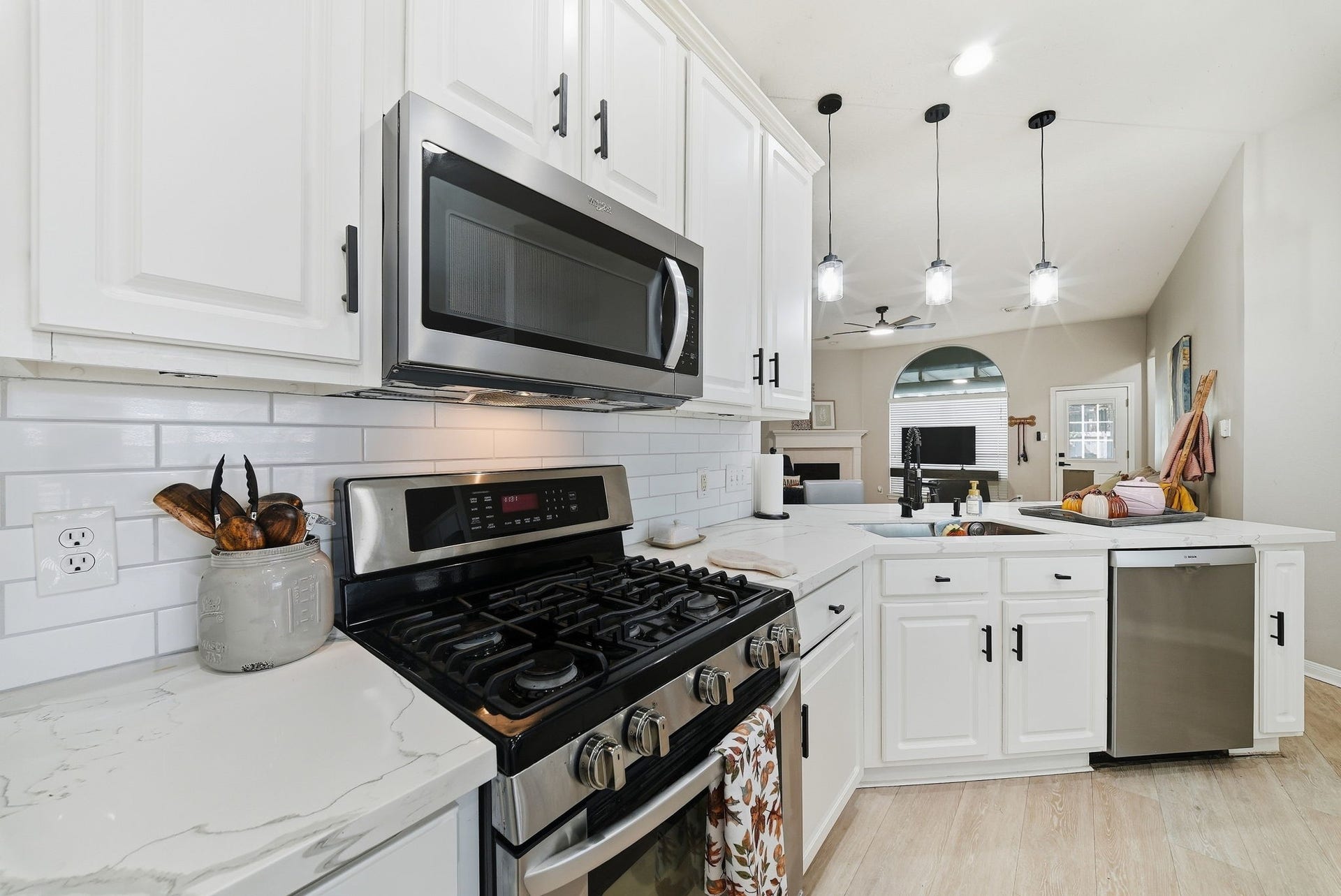 402 Prattwood Court, League City, TX 77573 Updated kitchen with gas range, built-in microwave, white cabinetry, quartz countertops, subway tile backsplash, and stainless steel dishwasher.