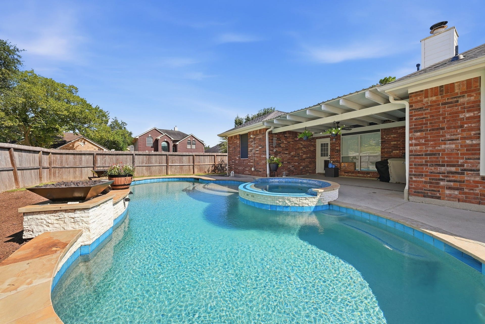 402 Prattwood Court, League City, TX 77573 Expansive backyard pool with raised spa, covered patio, brick exterior, and fenced yard.