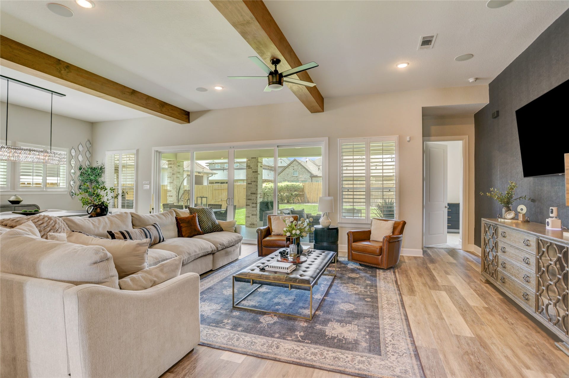 10615 Parkwood Court, Missouri City, TX 77459 Designed for effortless indoor-outdoor living, this inviting main living space showcases exposed wood beams, expansive windows, and oversized sliding glass doors that flood the home with natural light. The open-concept layout seamlessly connects the family room, dining area, and covered patio, creating the perfect setting for both entertaining and everyday living.