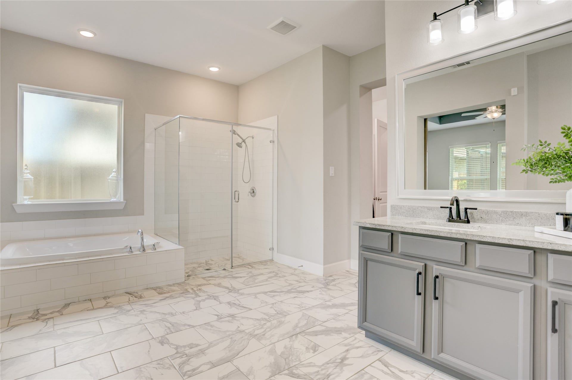 10615 Parkwood Court, Missouri City, TX 77459 The spacious primary bathroom offers a bright, relaxing retreat with an oversized glass-enclosed shower, dual-sink vanity, generous cabinetry, and elegant neutral finishes throughout.