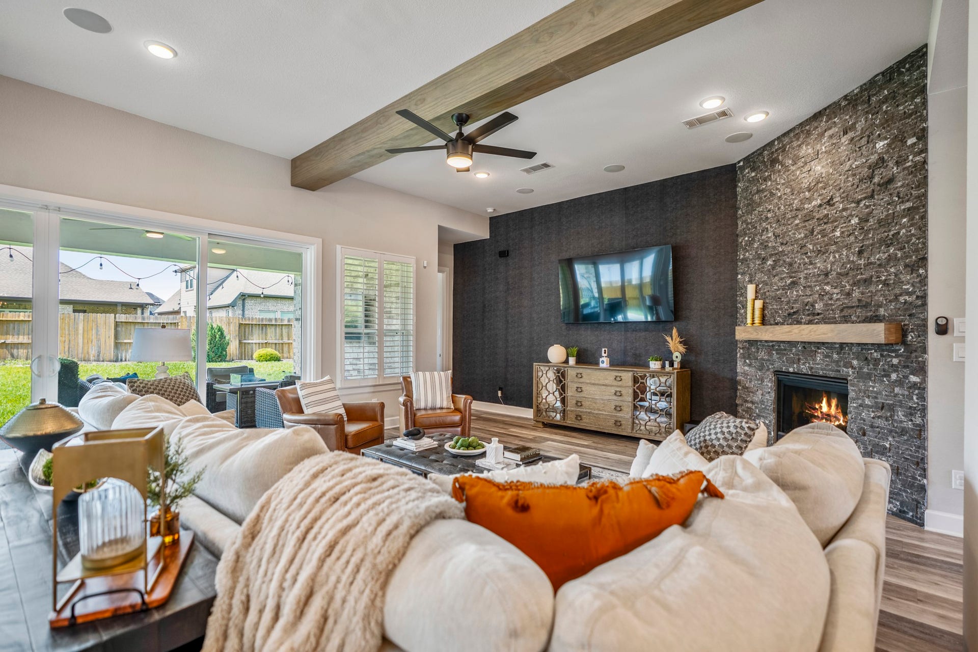 10615 Parkwood Court, Missouri City, TX 77459 Beautifully designed living area featuring a custom designer accent wall that adds depth, texture, and modern sophistication to the space. Paired with exposed wood beams, a dramatic stone fireplace, and expansive sliding doors overlooking the backyard, this room was thoughtfully curated for elevated everyday living and entertaining.