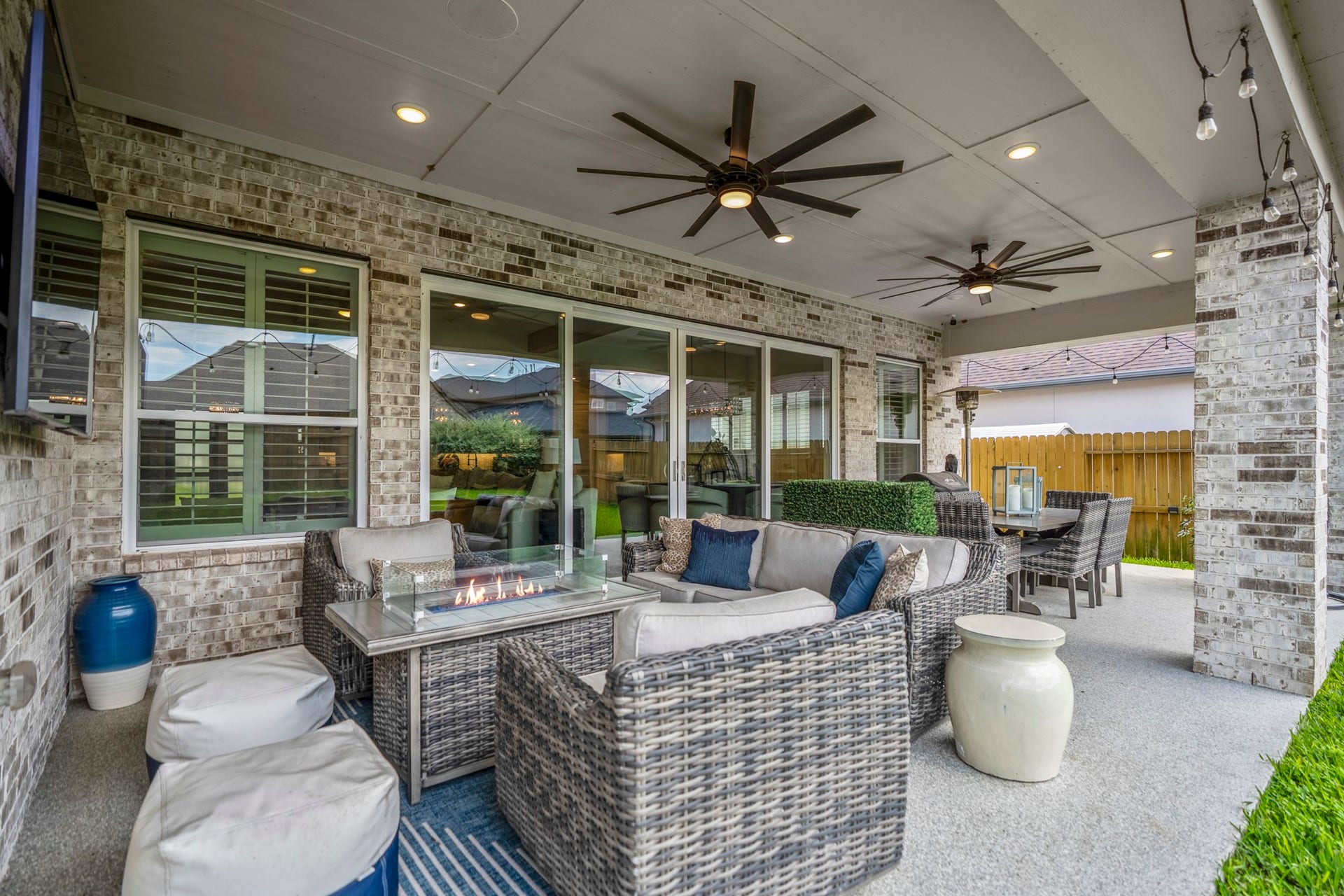 10615 Parkwood Court, Missouri City, TX 77459 Extended covered patio designed for year-round outdoor living, complete with dual ceiling fans, expansive sliding glass doors, and multiple seating areas perfect for entertaining or relaxing evenings at home.