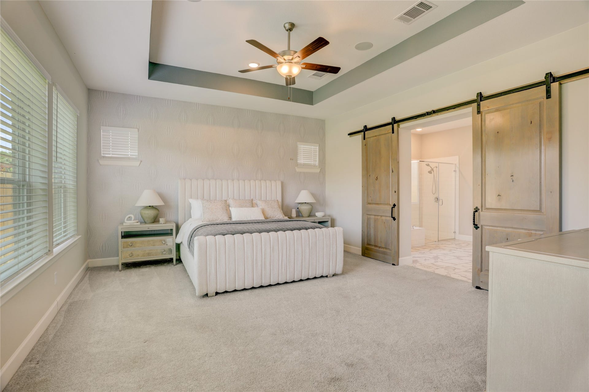 10615 Parkwood Court, Missouri City, TX 77459 Luxurious primary suite designed as a true retreat, featuring elegant barn doors, a tray ceiling with custom accent paint, and designer wallpaper creating a stunning focal point behind the bed. The spacious layout, elevated finishes, and warm designer touches combine to create a sophisticated and relaxing atmosphere.