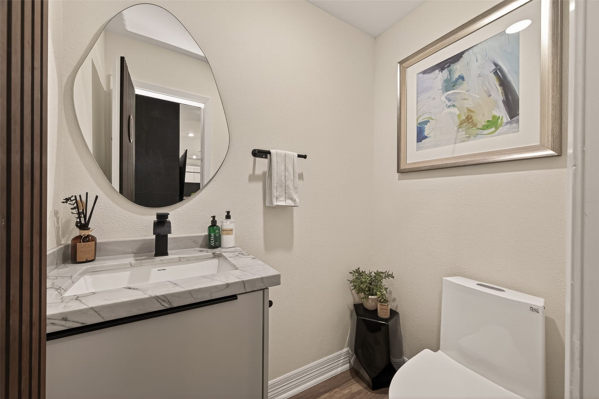 5422 Valerie Street, Bellaire, TX 77401 This discreetly located half bath features a sleek design with a marble countertop, oval mirror, and contemporary fixtures.