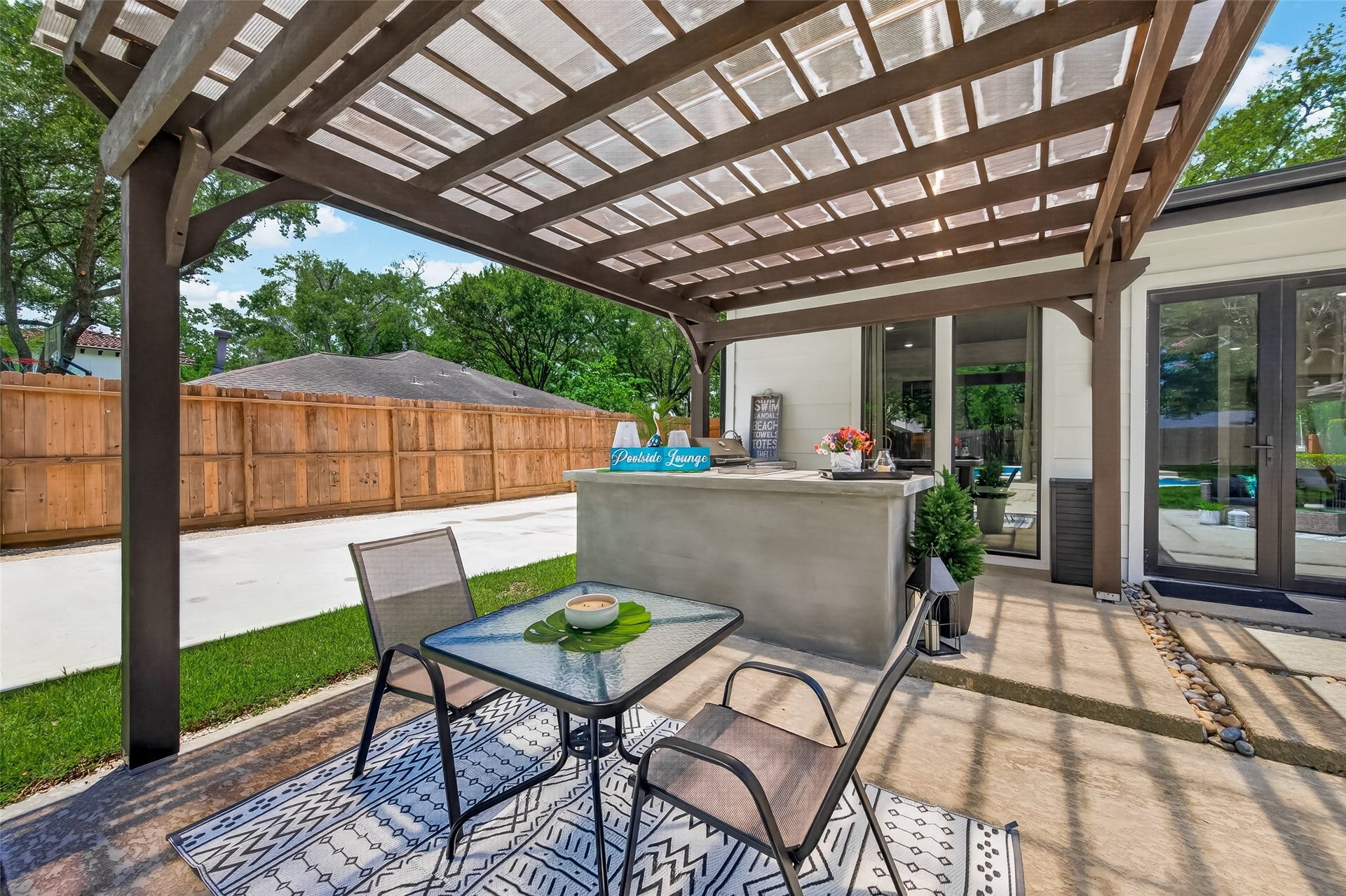 5422 Valerie Street, Bellaire, TX 77401 This backyard features a stylish pergola and an outdoor kitchen, creating an ideal setting for entertaining and relaxed outdoor living.