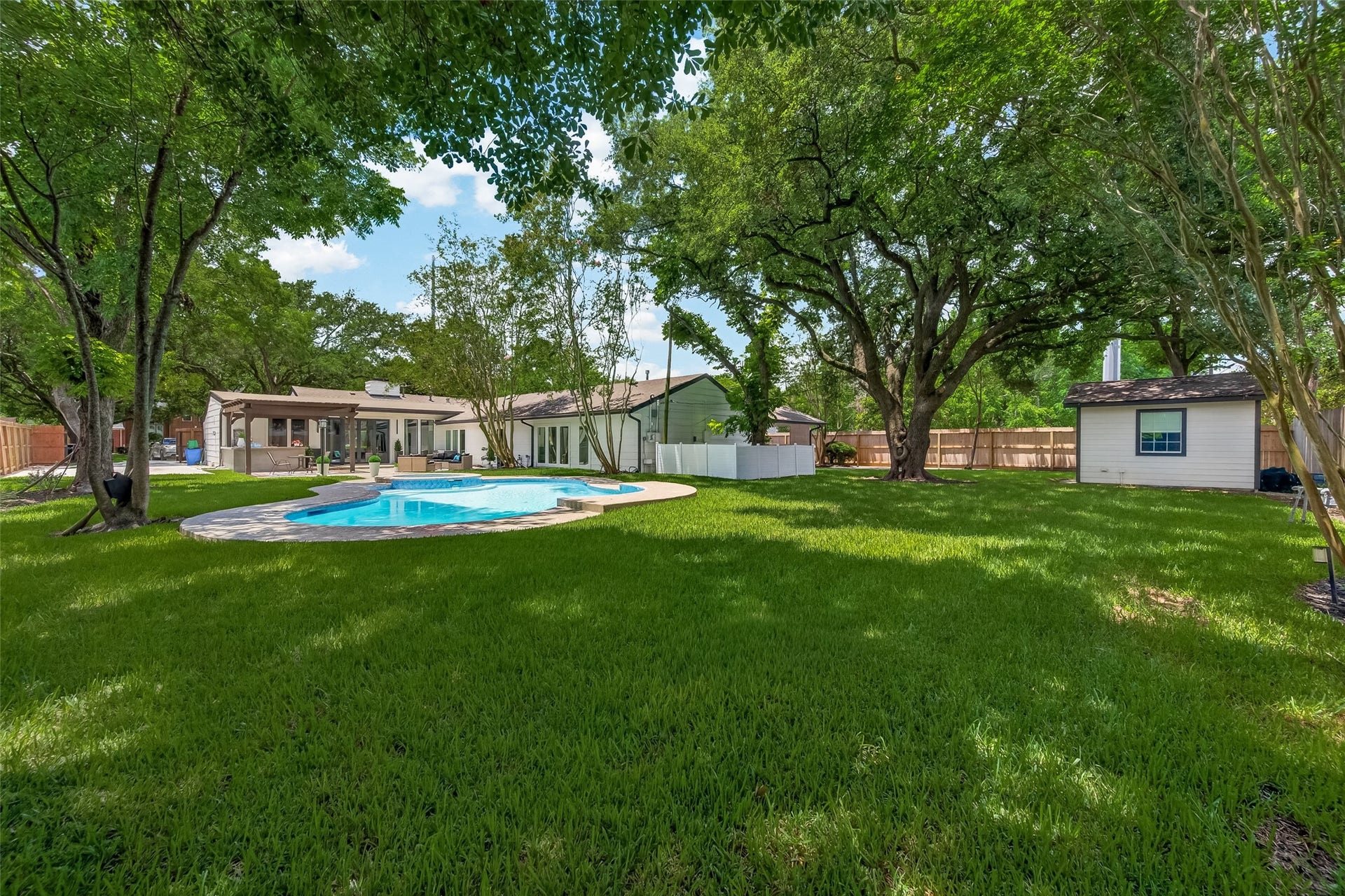 5422 Valerie Street, Bellaire, TX 77401 A beautiful outdoor space featuring a sparkling pool, paved deck, and mature trees that create a naturally shaded retreat. The perfect backdrop to relax, entertain, and enjoy year-round outdoor living.