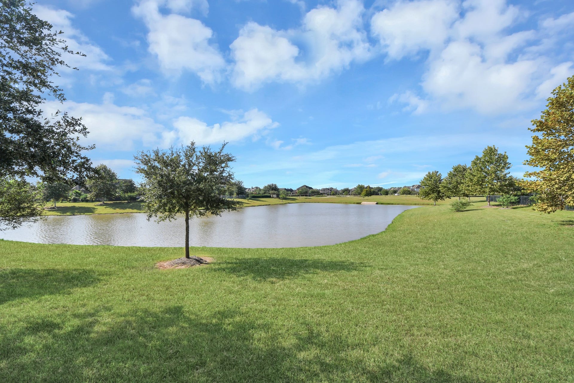 1423 Hackberry Heights Drive, Richmond, TX 77406 Serene lakeside view with lush green lawns and scattered trees, perfect for relaxation and outdoor enjoyment.