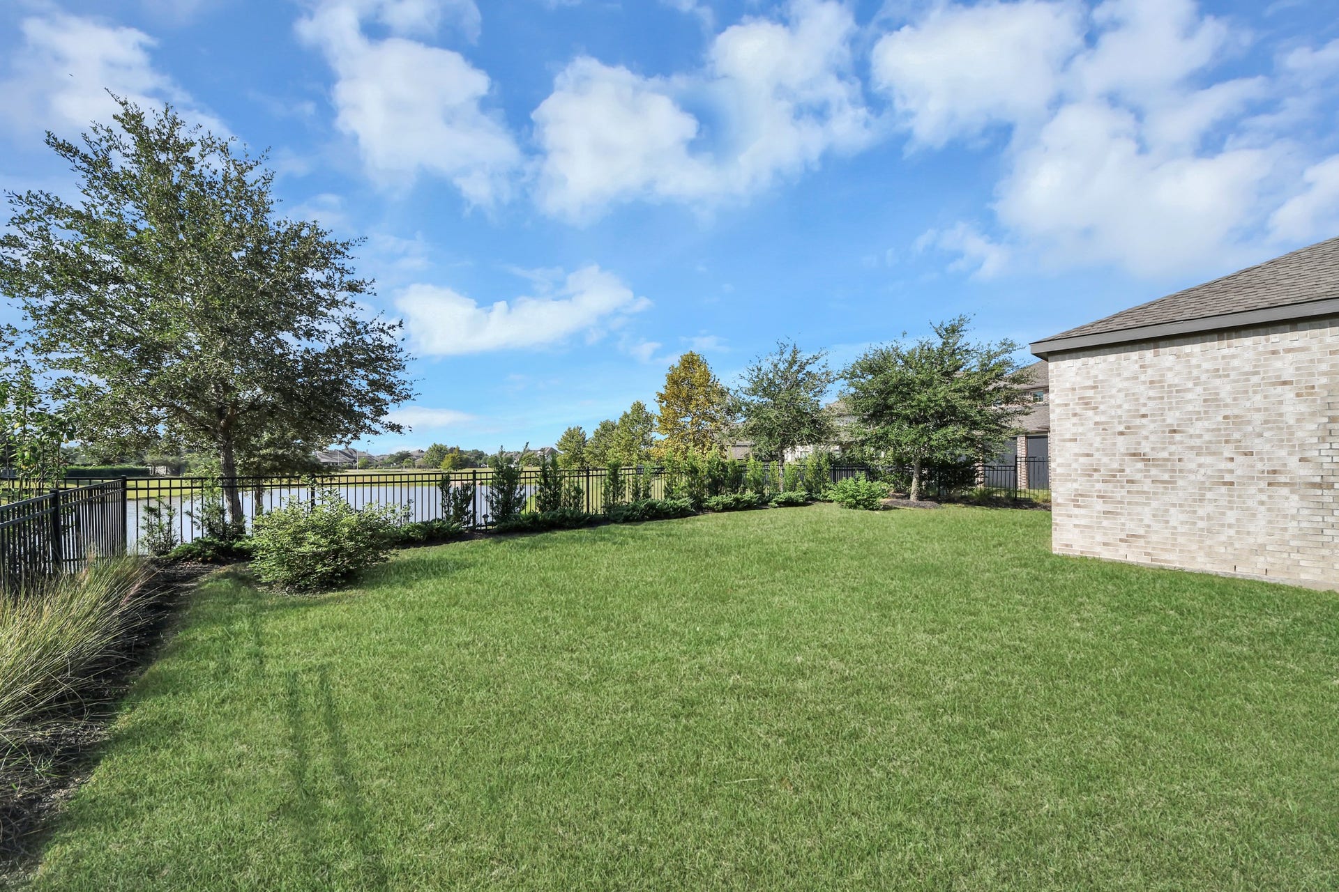 1423 Hackberry Heights Drive, Richmond, TX 77406 Spacious backyard with lush green lawn, bordered by a charming fence and mature trees, offering serene water views.