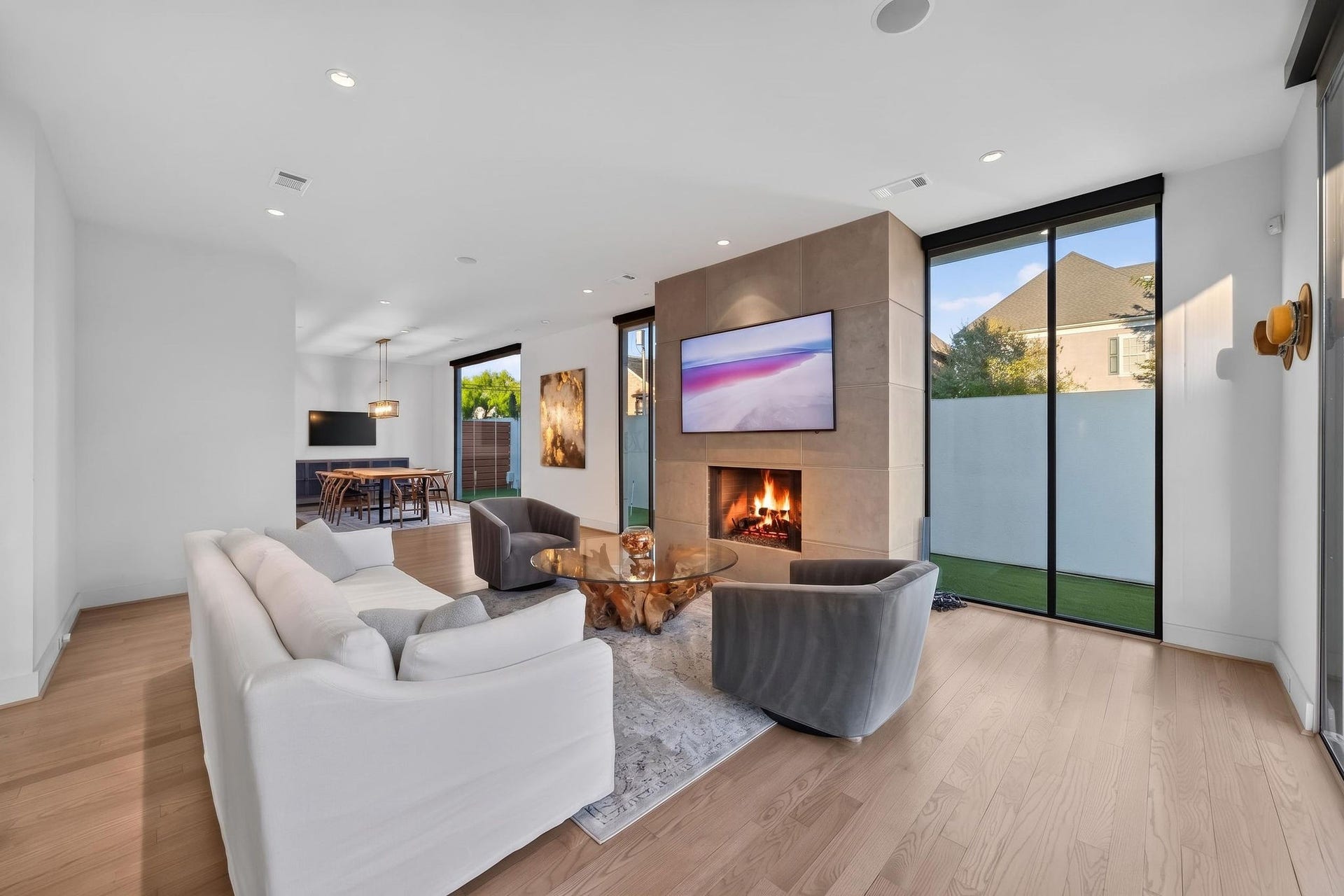 6002 Valley Forge Drive, Houston, TX 77057 Elegant living room featuring a modern fireplace, expansive windows for natural light, and sleek hardwood floors.