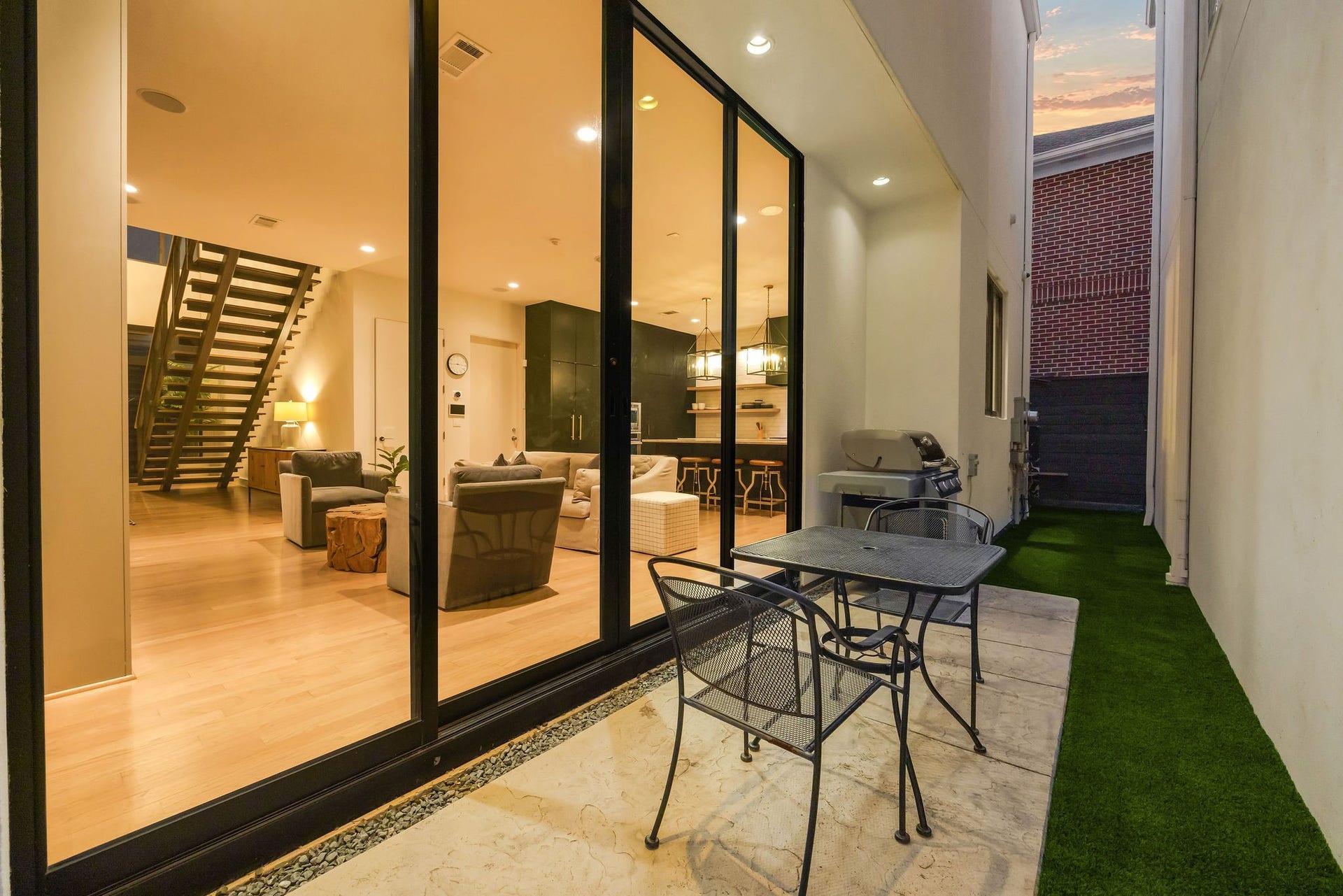 6002 Valley Forge Drive, Houston, TX 77057 Modern patio with sleek glass doors opening to a stylish living area featuring elegant lighting and contemporary furnishings, perfect for indoor-outdoor entertaining.